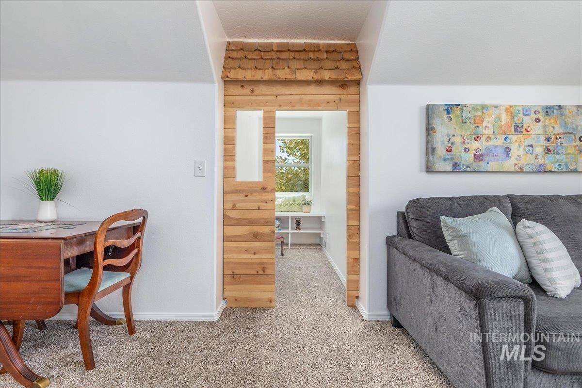Carpeted room featuring a distinctive cedar-paneled archway with a shingled roof detail