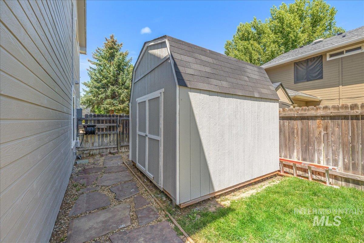 Detached gambrel-roof shed with double doors, wood-finish siding, and shingle roofing