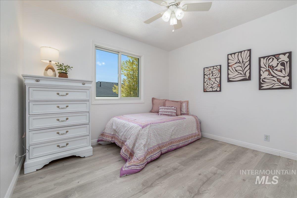 Light-filled room featuring a ceiling fan with integrated lighting, wood-finish flooring, and a window providing natural illumination