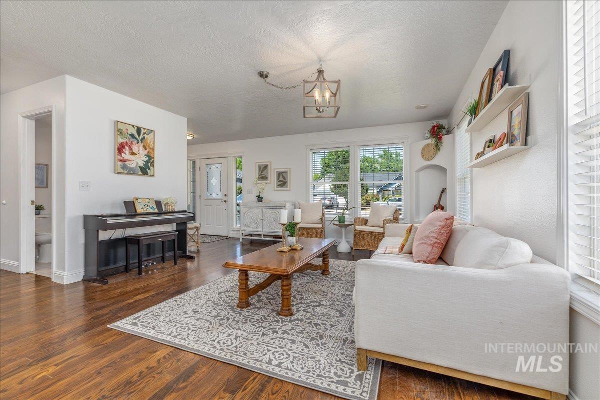 Spacious living area featuring rich wood-finish flooring, a decorative area rug, and ample natural light through multiple windows