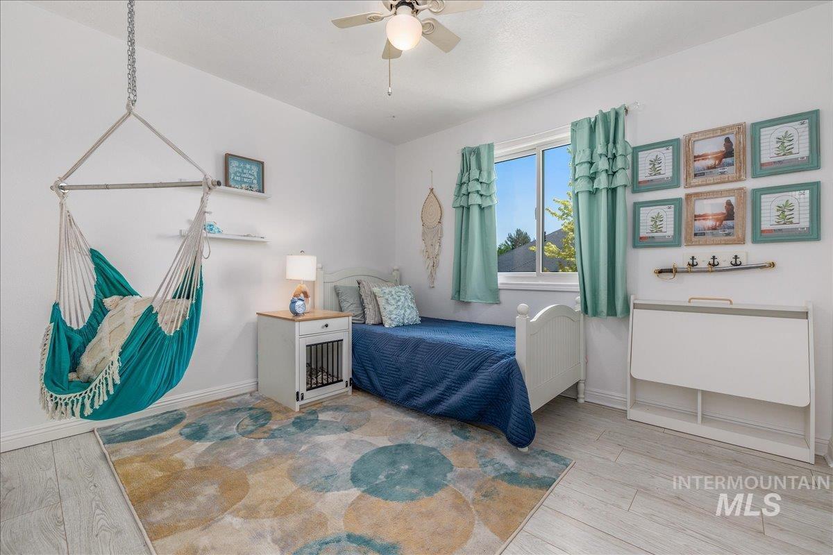 Light wood-finish flooring and white walls define this room, featuring a white window frame with light blue window treatments