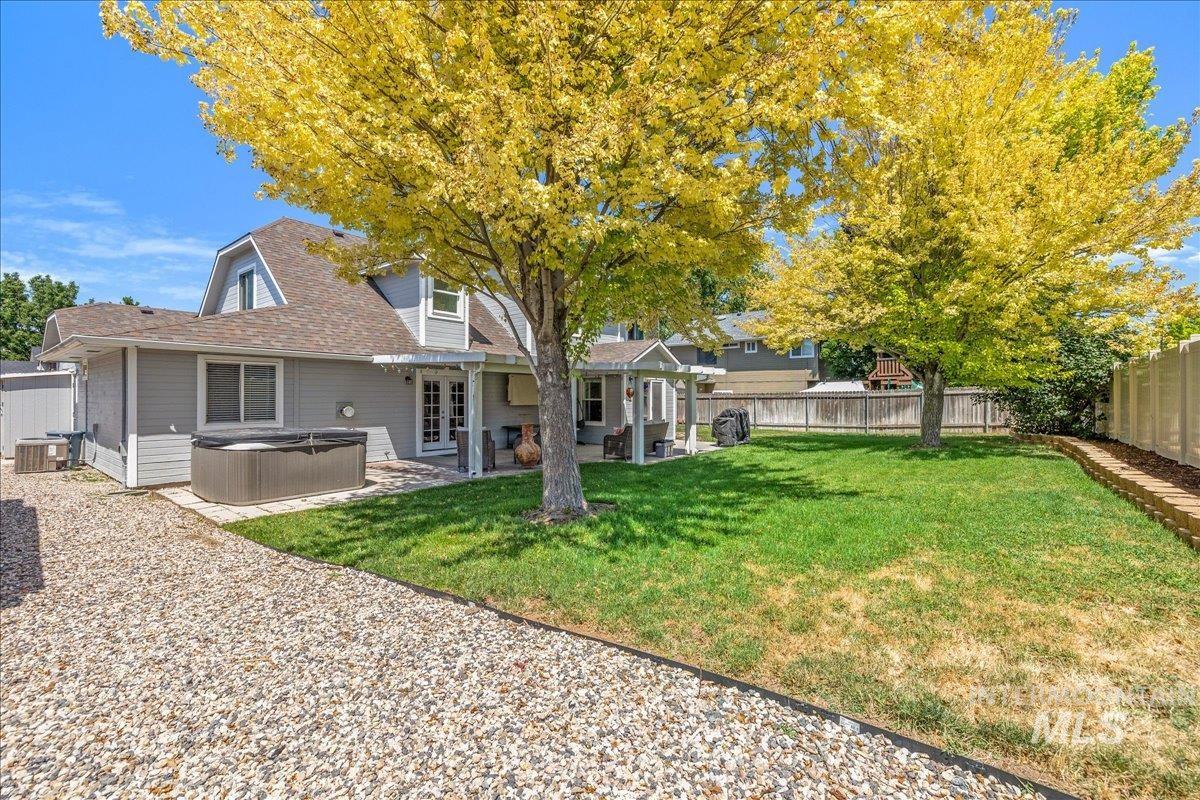 Expansive backyard featuring a manicured lawn, established trees, and a gravel pathway