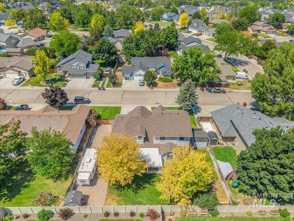 Expansive property featuring a spacious backyard, established landscaping with mature trees, a gravel side yard, and a large shed