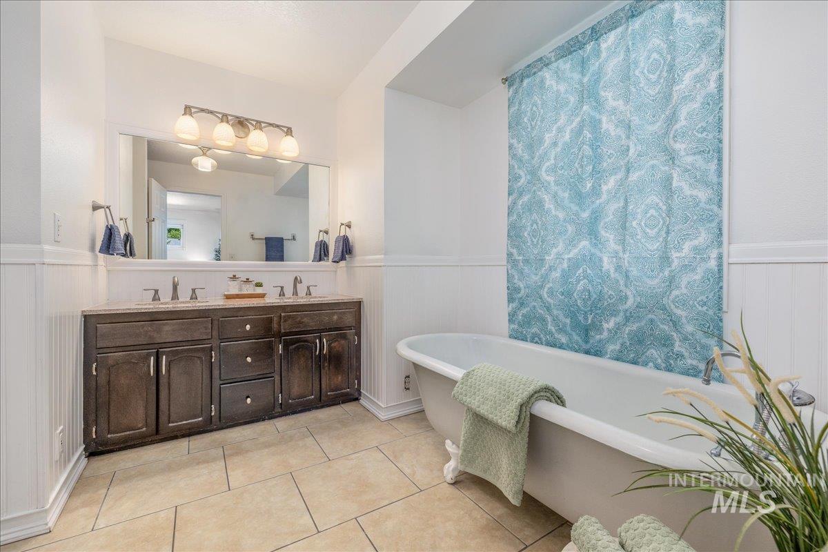 Bathroom featuring a clawfoot tub, dual vanity with undermount sinks, and tile flooring