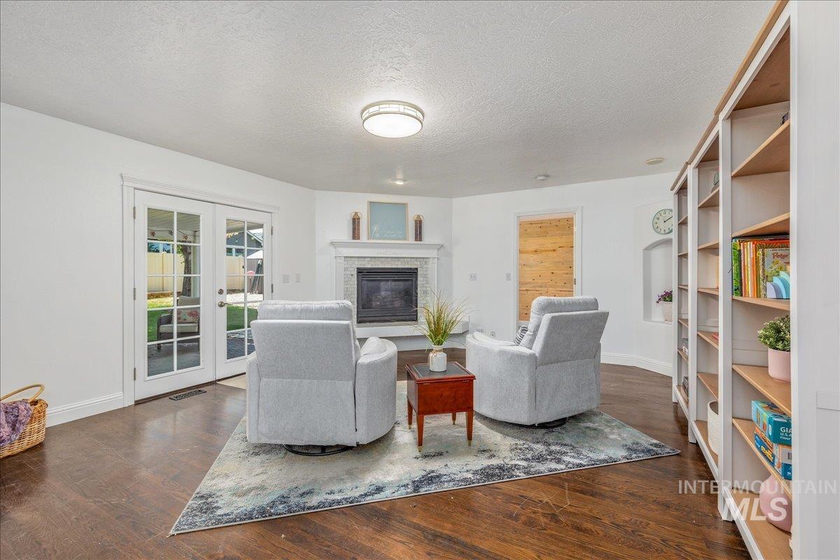 Living area featuring dark wood-finish flooring and a corner fireplace with a tile surround and mantel
