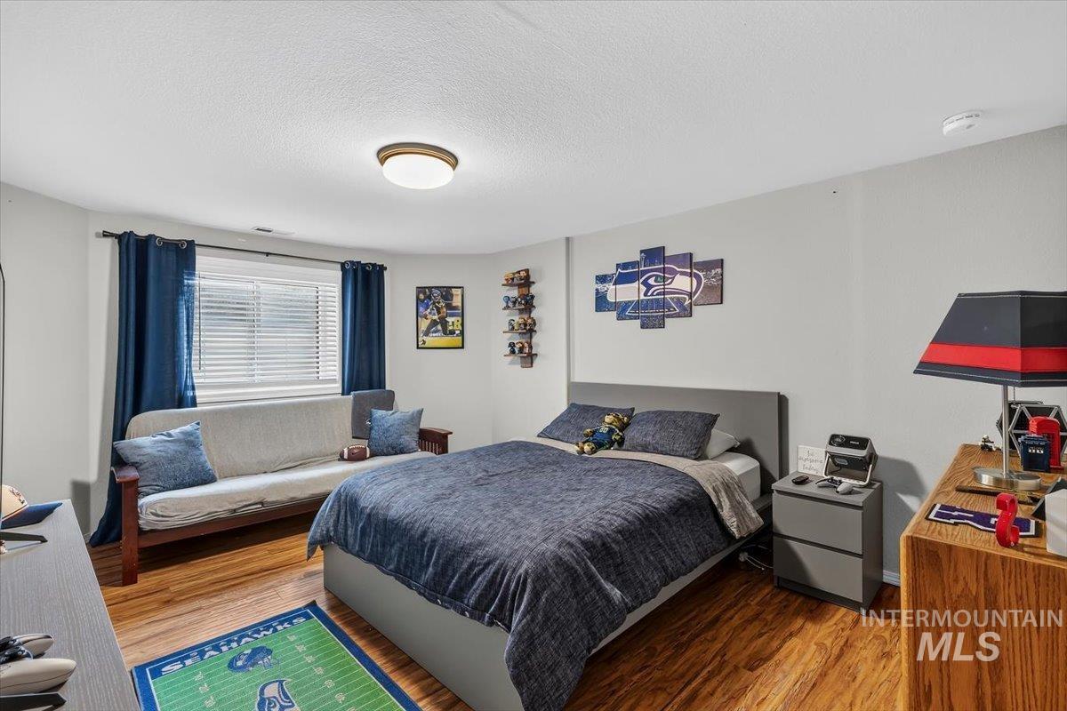 Room featuring wood-finish flooring, a window with blinds, and light-toned walls
