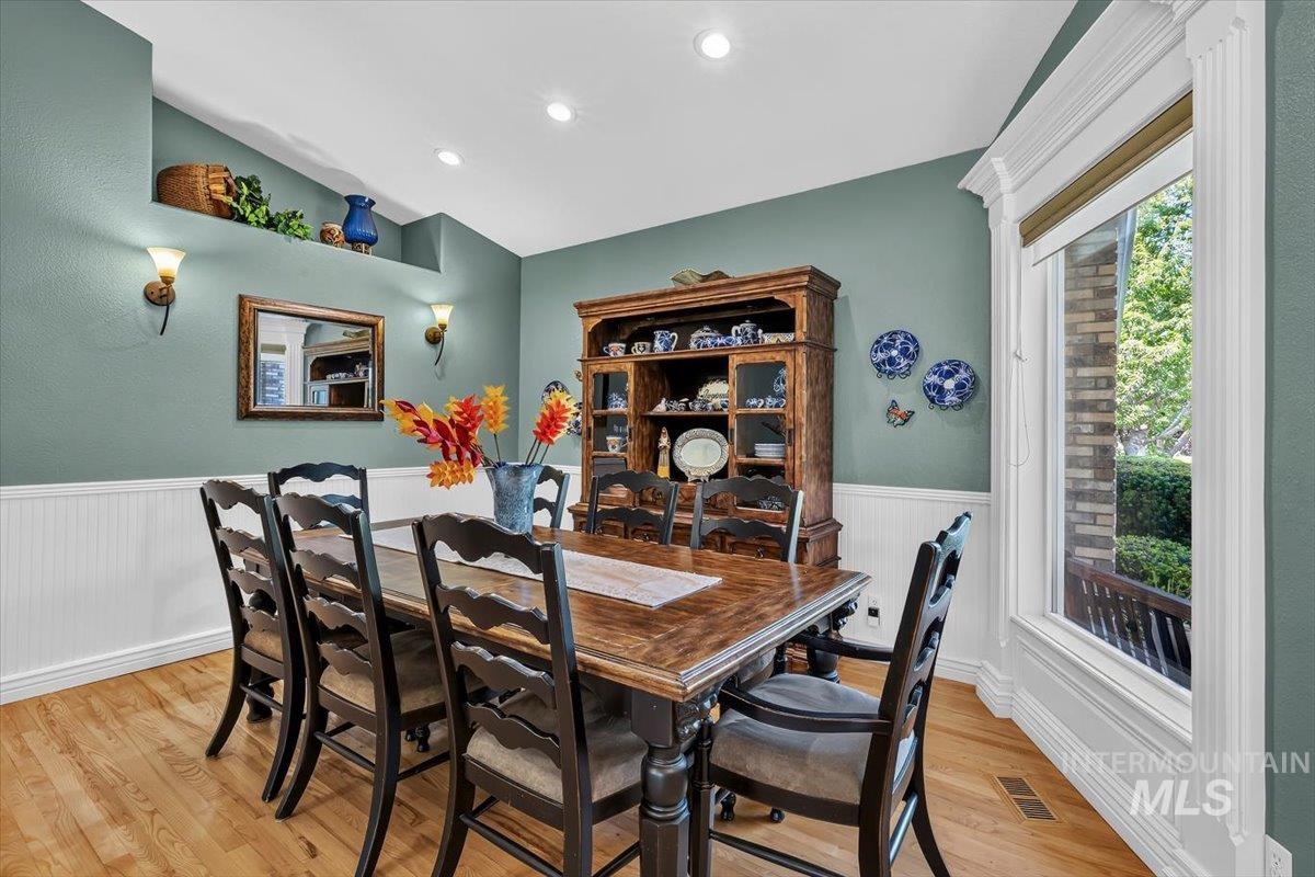 Formal dining area featuring hardwood-finish flooring, wainscoting, and recessed lighting