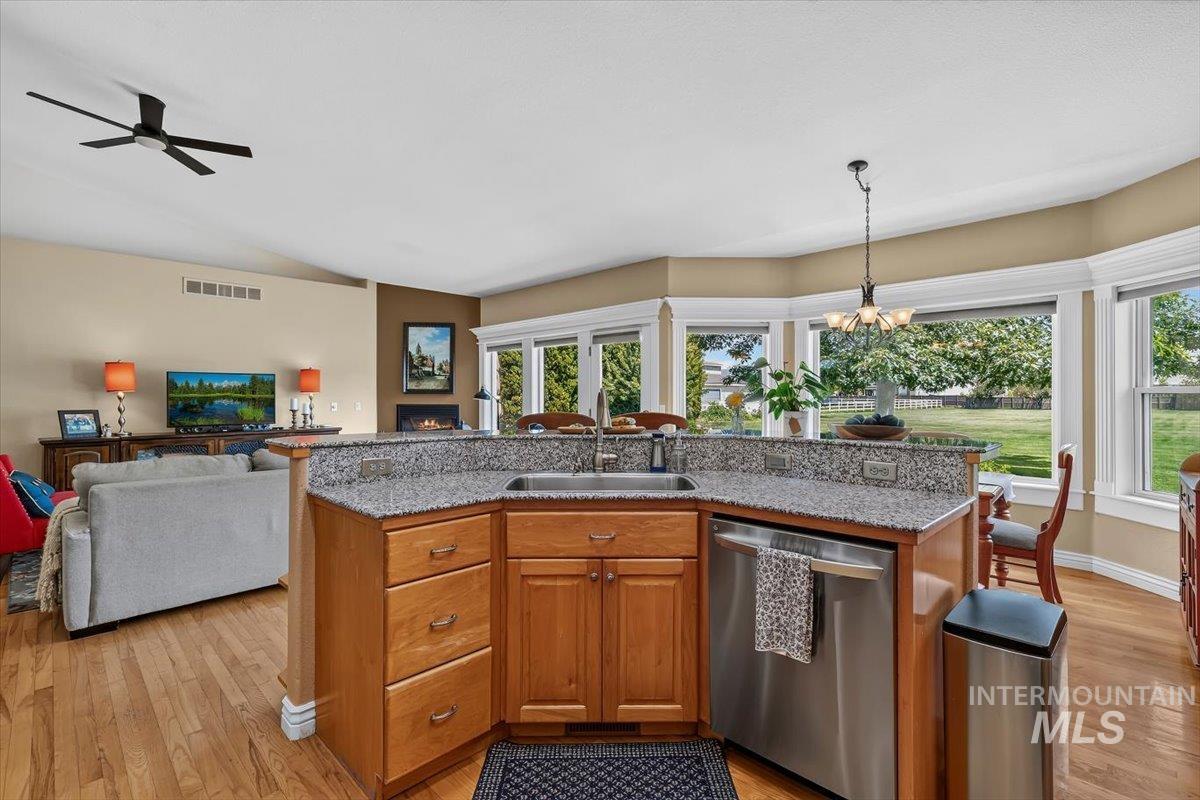 Kitchen peninsula with granite-finish countertop, undermount sink, and integrated stainless steel dishwasher