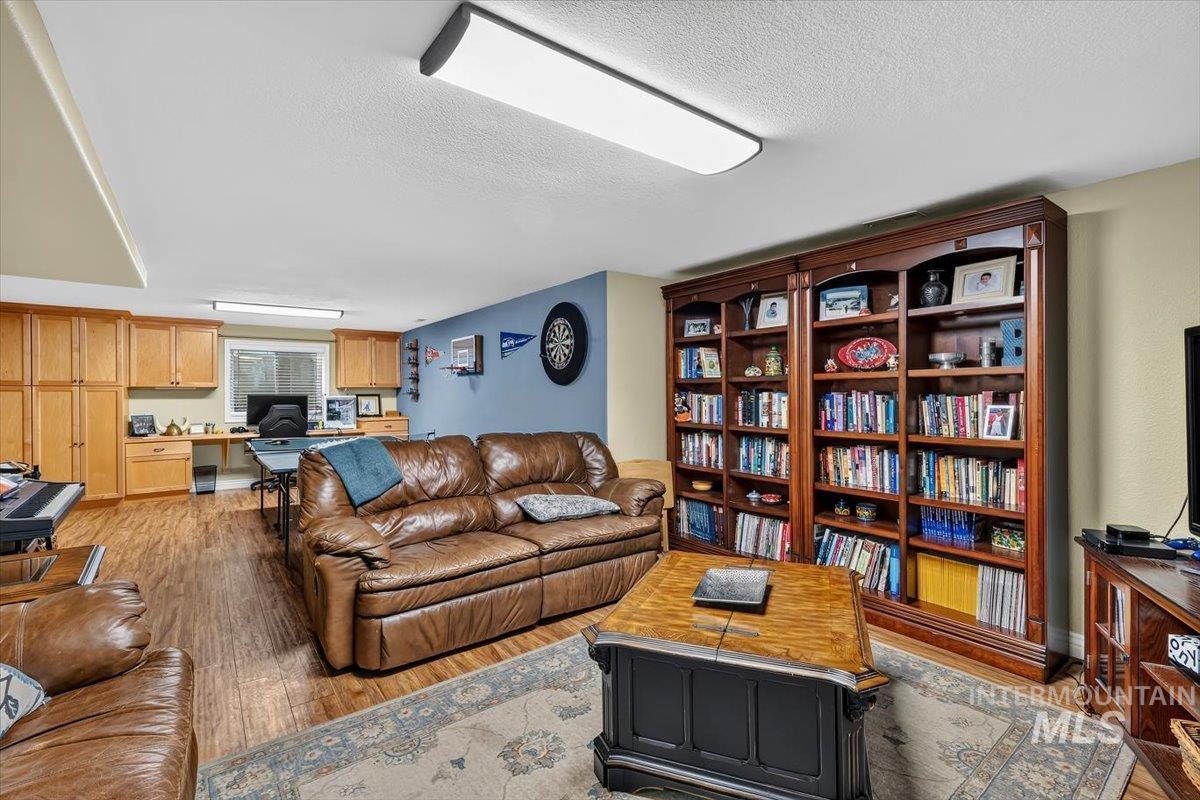Spacious finished area featuring wood-finish flooring, built-in cabinetry, an integrated desk space with window, and substantial built-in shelving