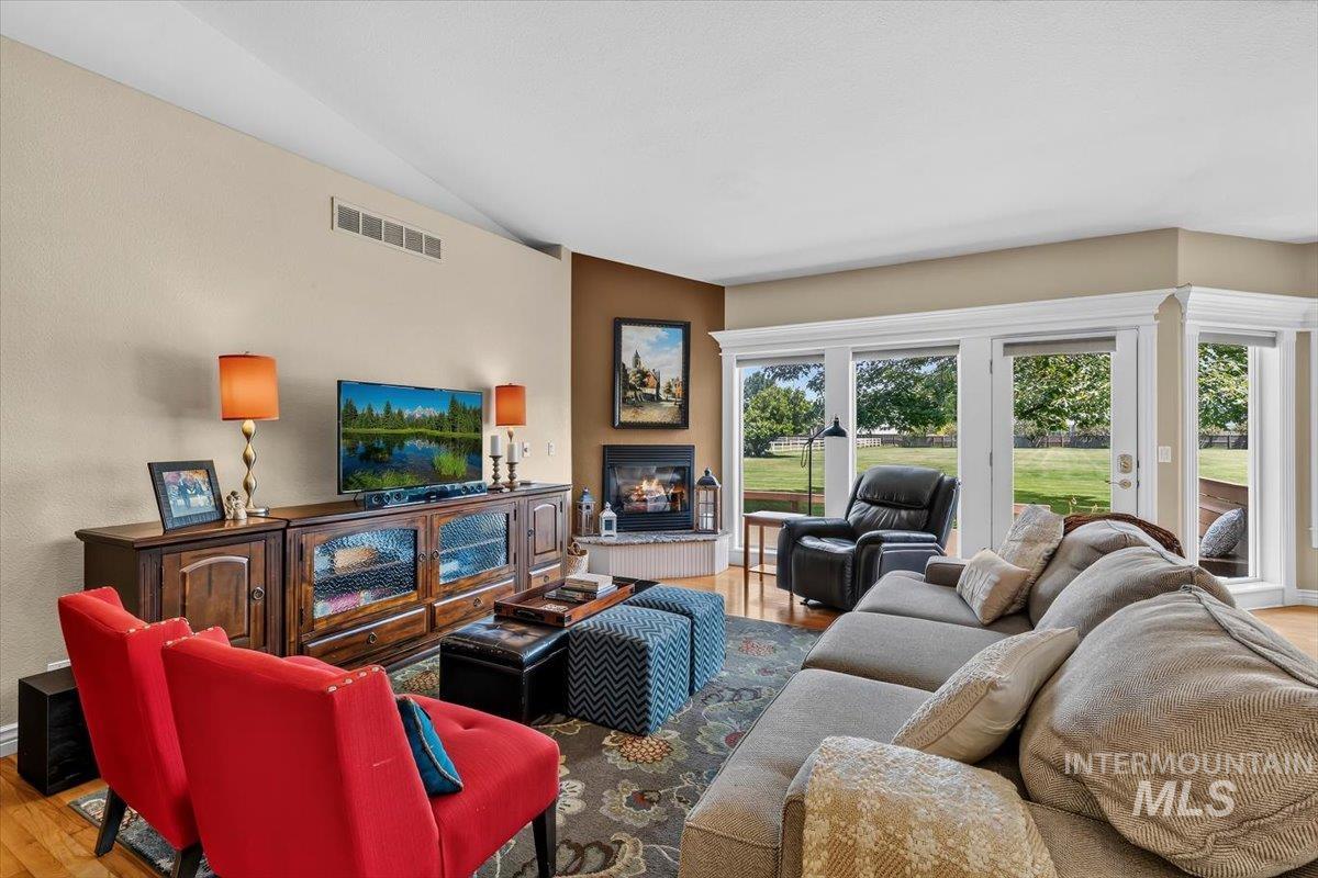 Living area featuring wood-finish flooring, a corner fireplace, and a wall of windows and glass doors leading to the exterior