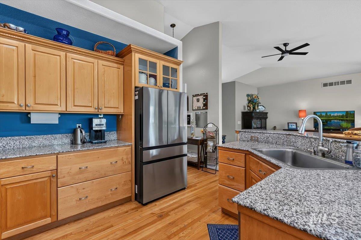 Kitchen featuring light wood cabinetry, speckled countertops, stainless steel refrigerator, and a double basin sink