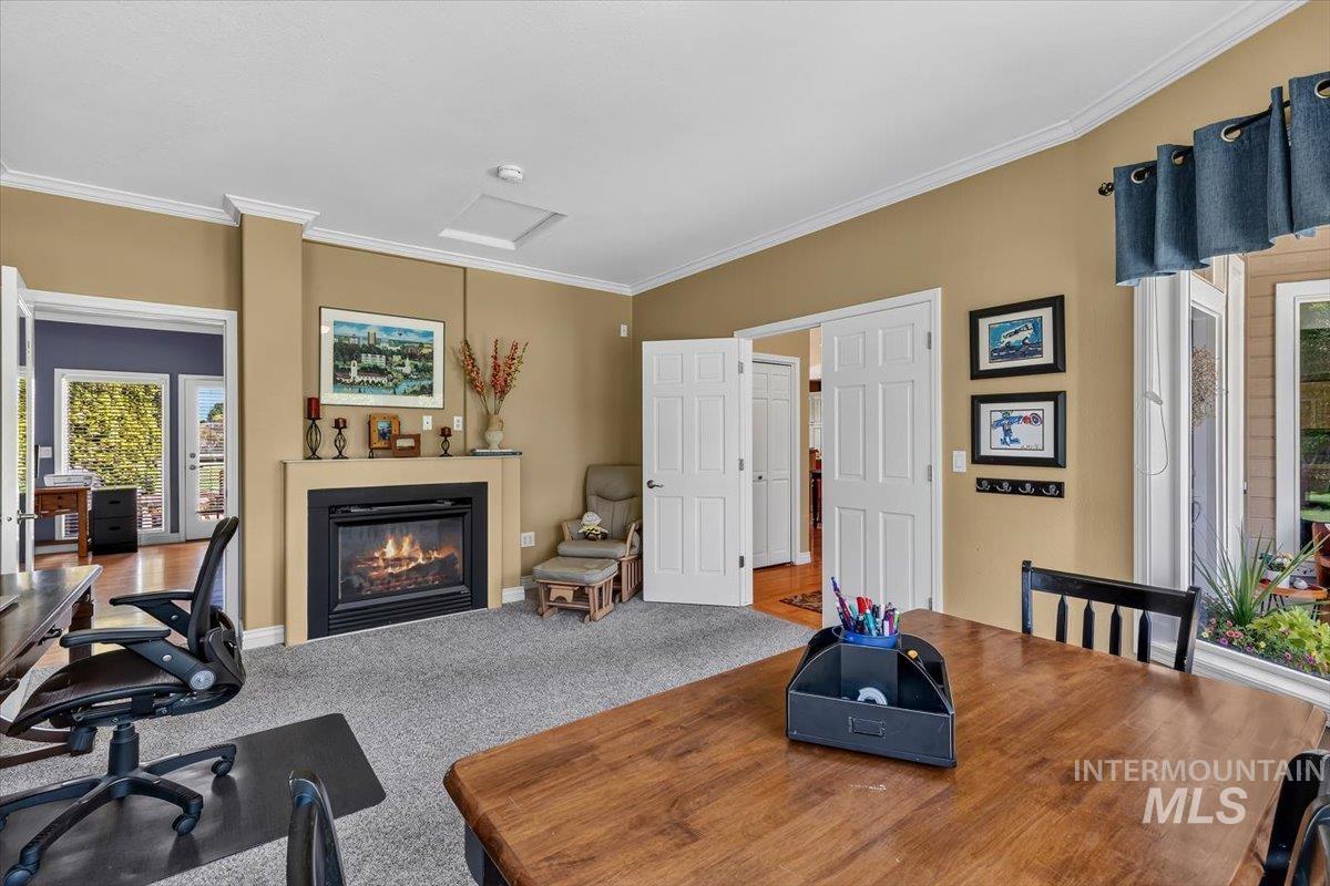 Carpeted room featuring a built-in fireplace with a stone-top mantel, crown molding, and a bay window