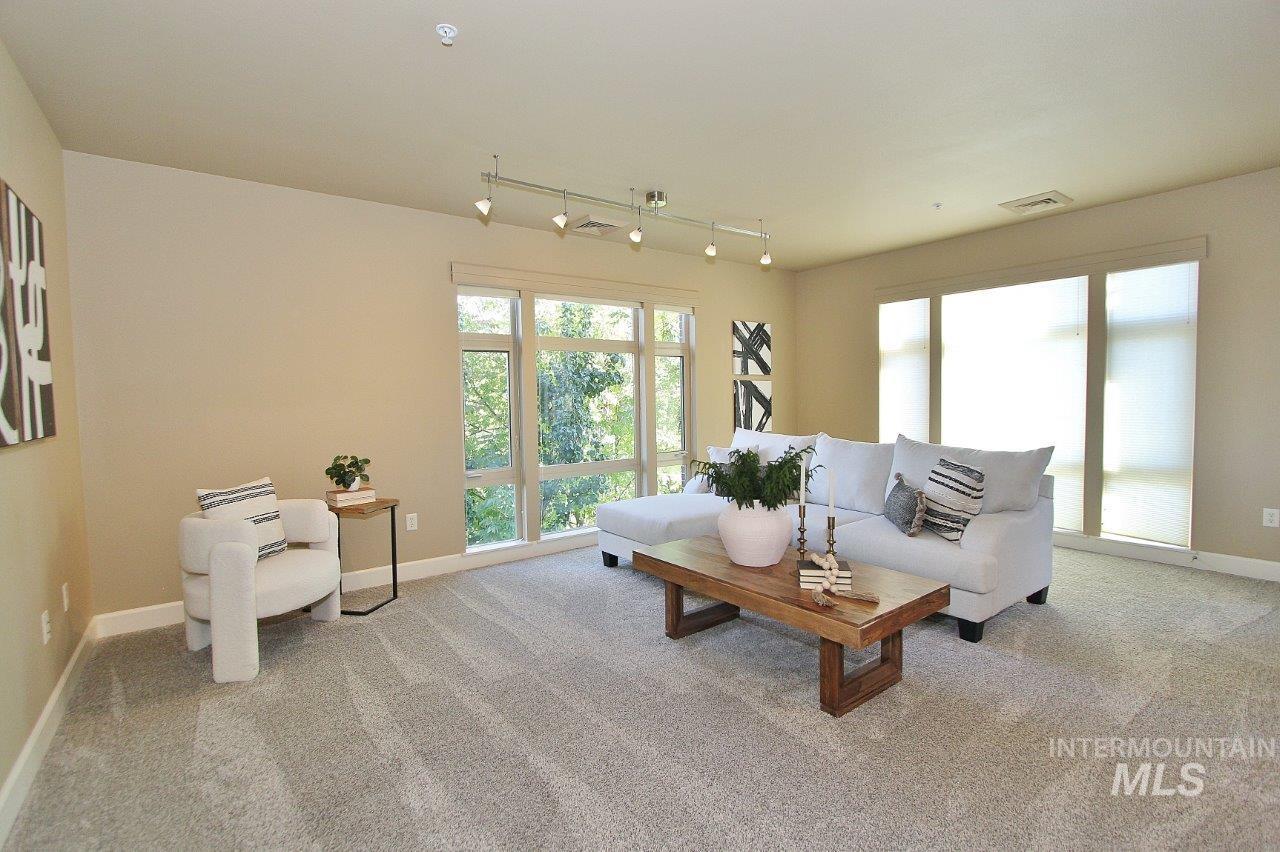 Carpeted living room with baseboards and track lighting