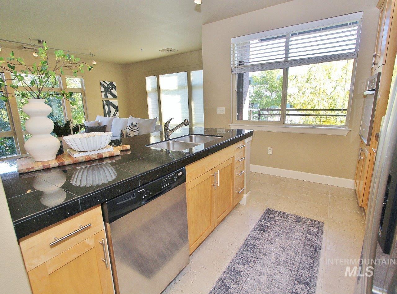 Kitchen with stainless steel appliances, tile counters, and light tile patterned flooring