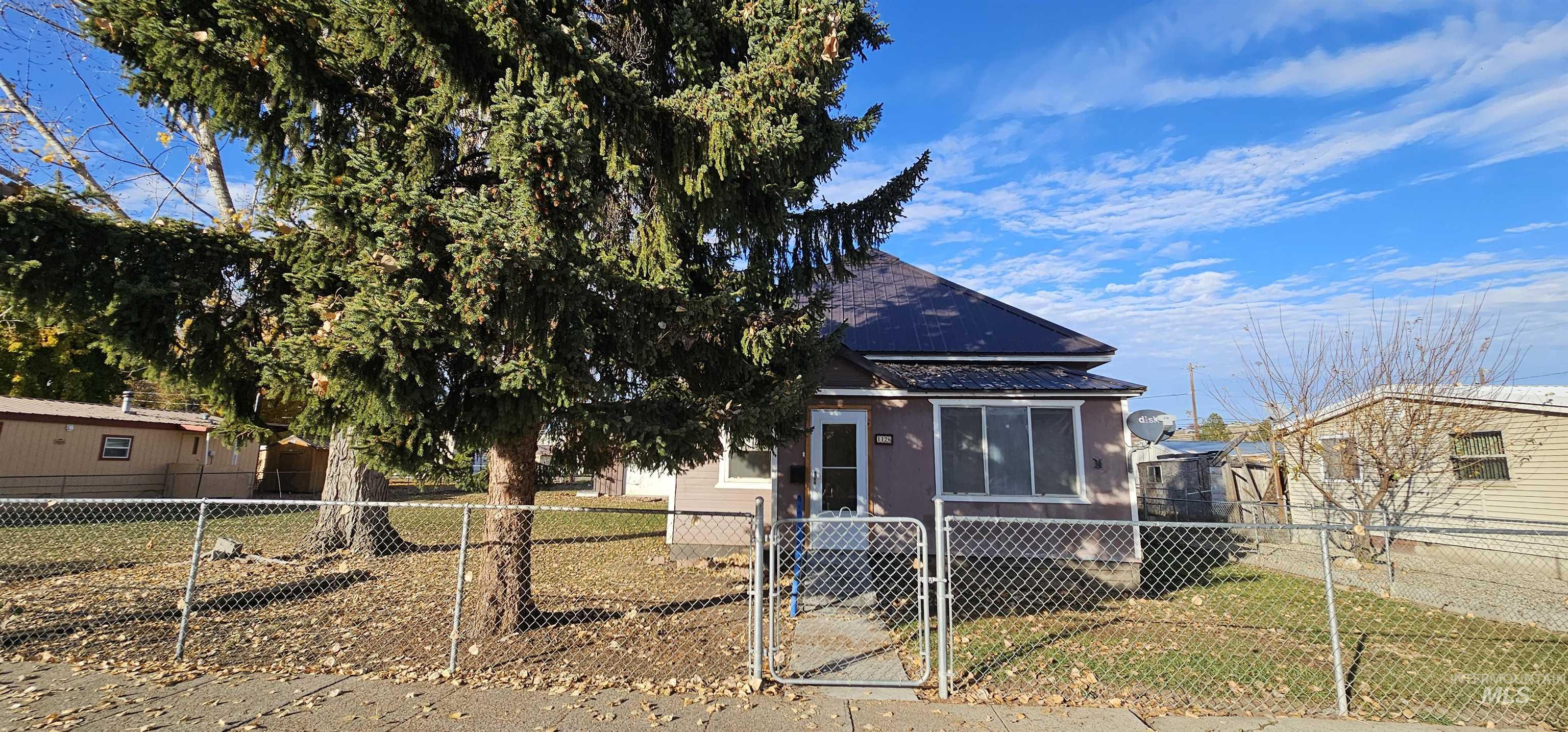 View of front of property featuring a gate, a fenced front yard, and a metal roof