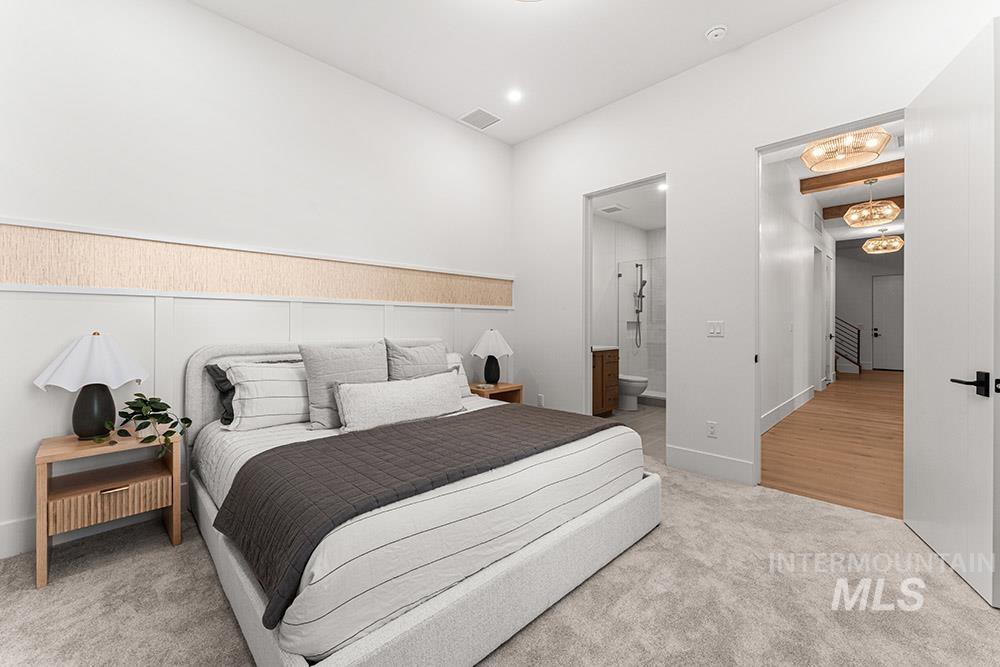 Bedroom featuring light carpet and connected bathroom