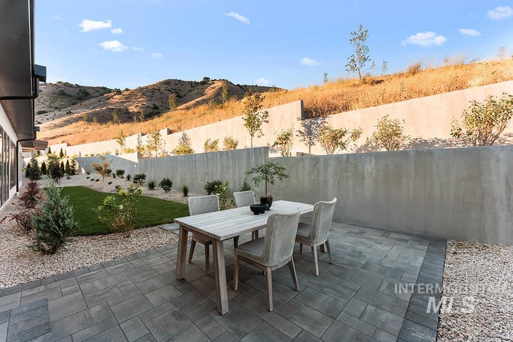 Fenced backyard featuring outdoor dining space, a patio, and a mountain view