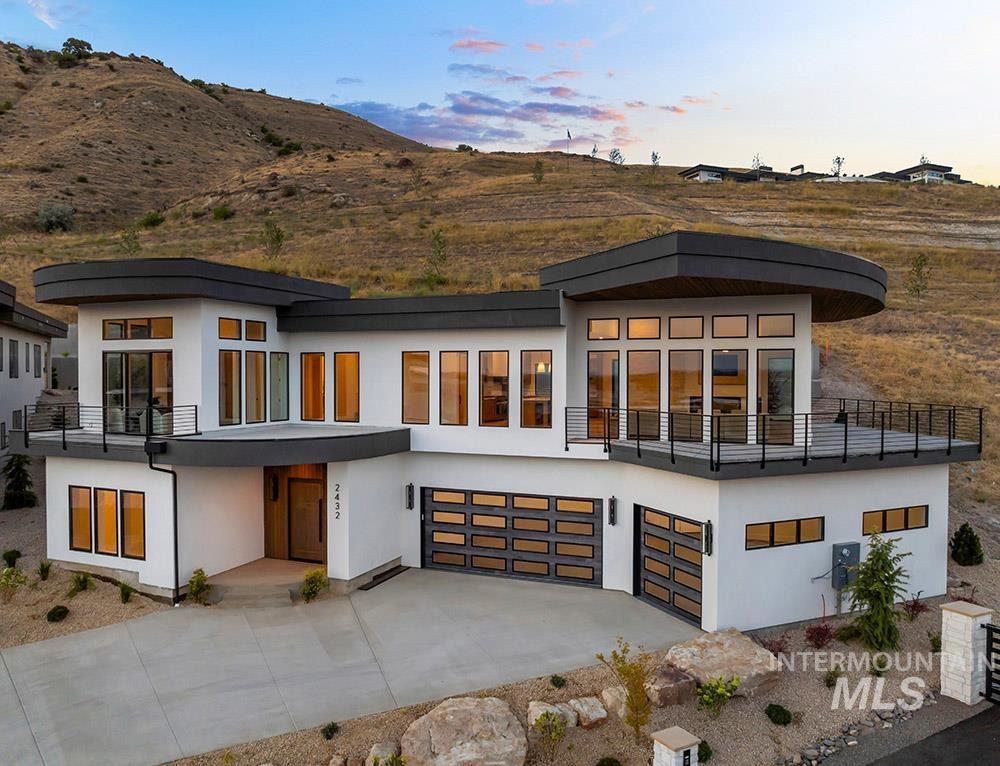 Back of house with a garage, concrete driveway, and stucco siding