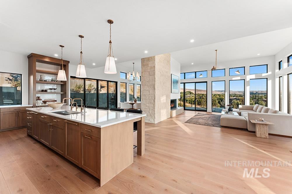Kitchen with open floor plan, decorative light fixtures, a chandelier, a kitchen bar, and a center island with sink