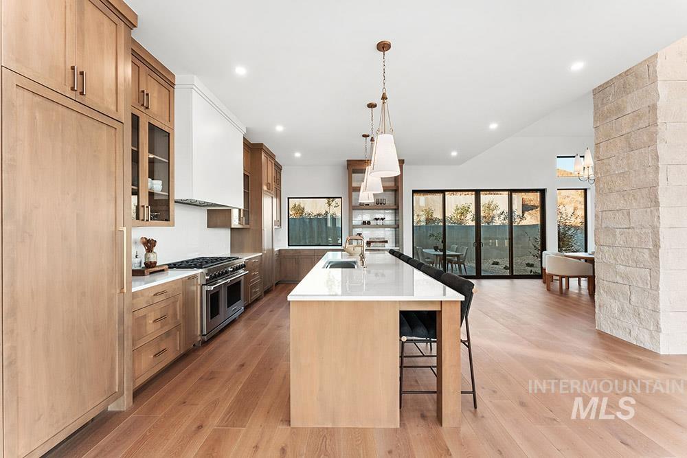 Kitchen featuring a kitchen breakfast bar, a large island with sink, decorative light fixtures, light wood finished floors, and recessed lighting