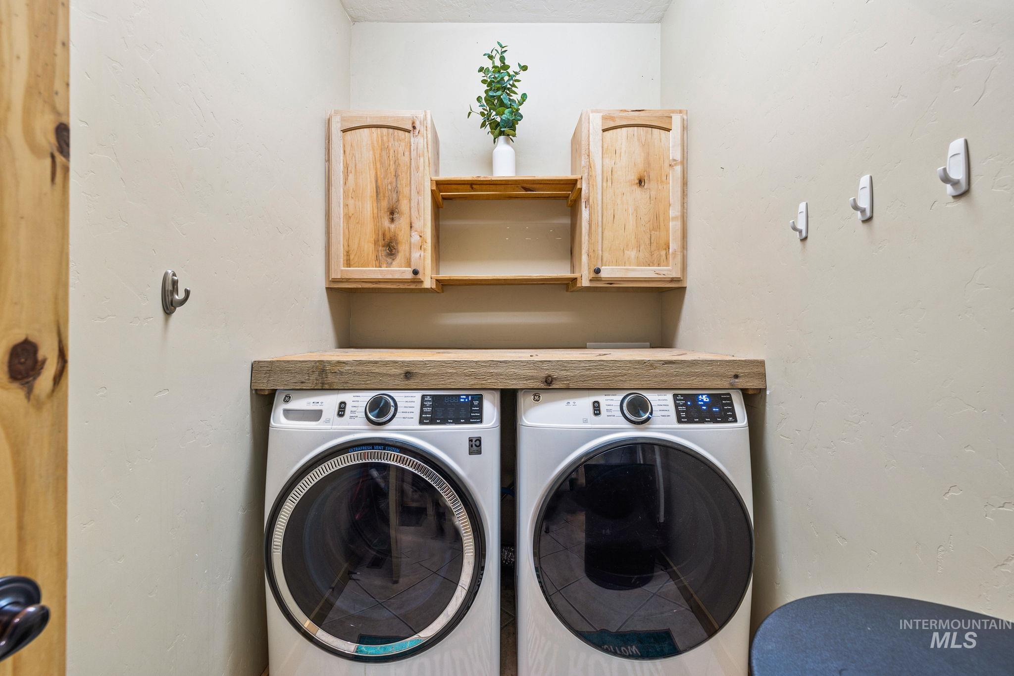 Laundry room featuring washer and dryer, a textured wall, and cabinet space