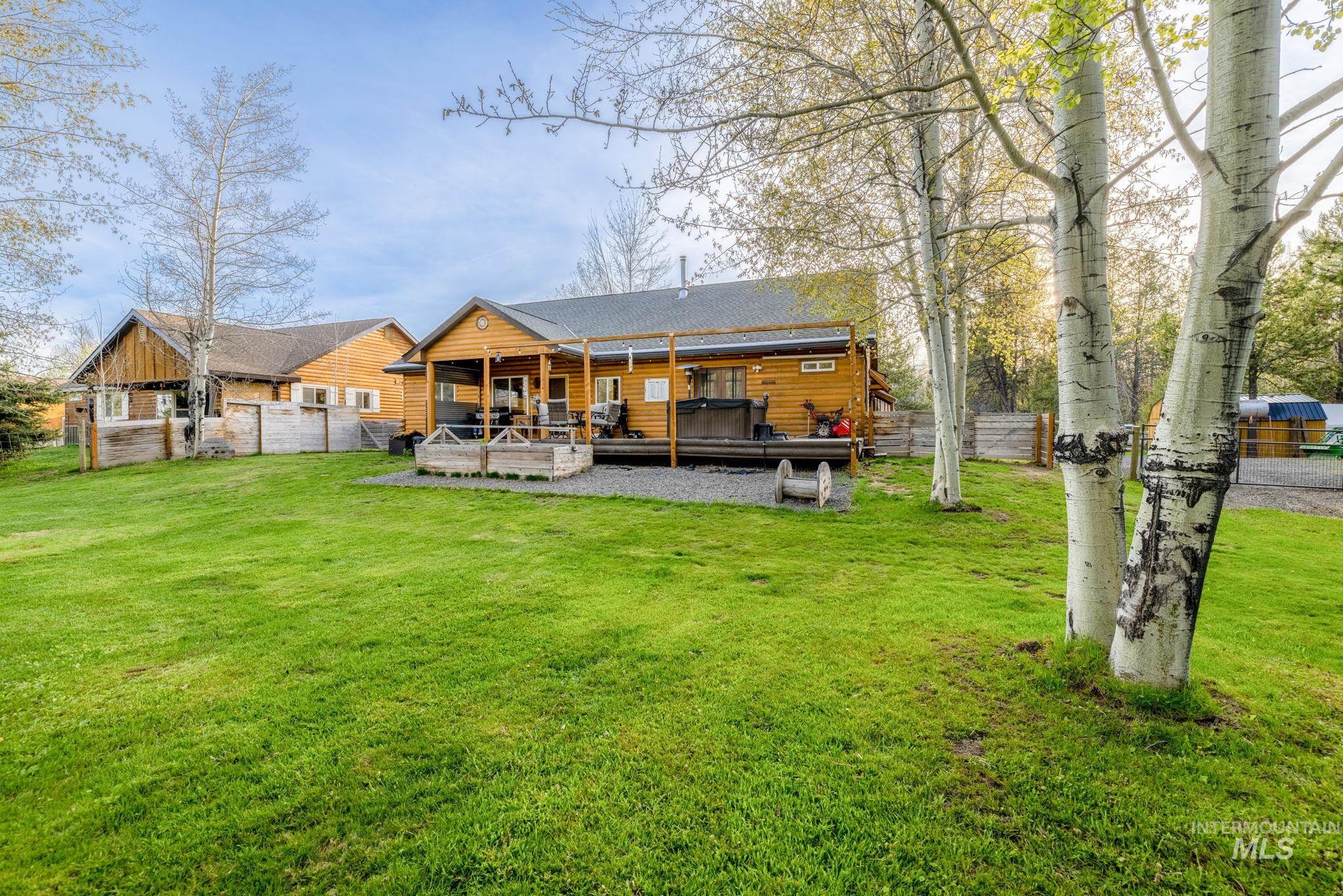 Back of house featuring a wooden deck, a jacuzzi, and log veneer siding