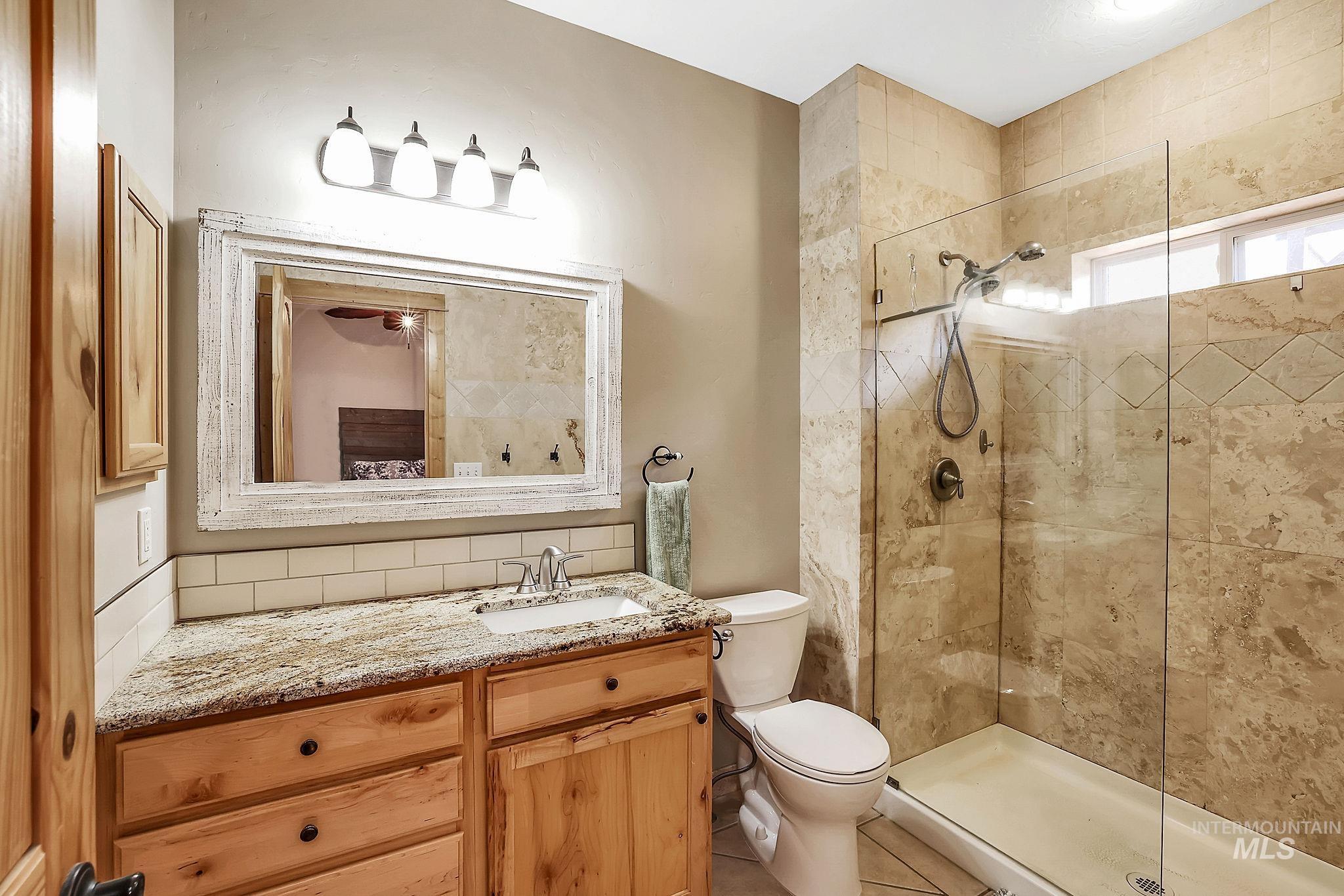 Full bathroom featuring backsplash, vanity, and a shower stall