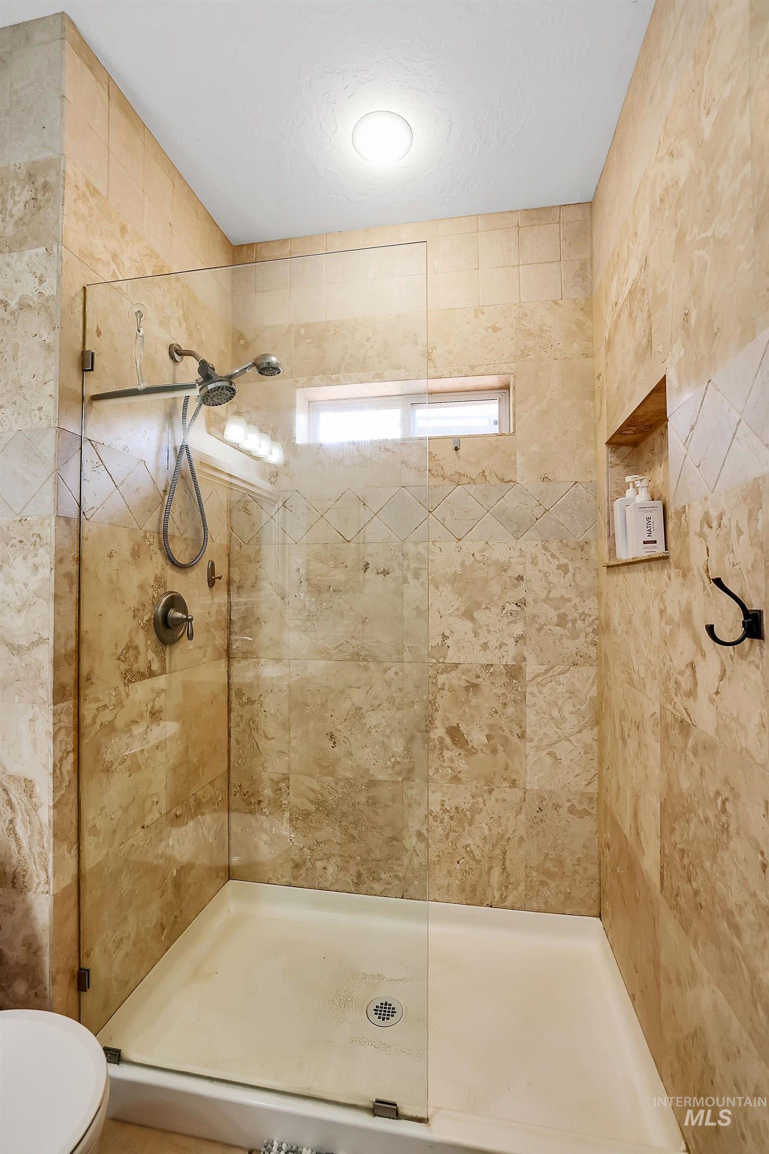 Full bath featuring toilet and a stall shower