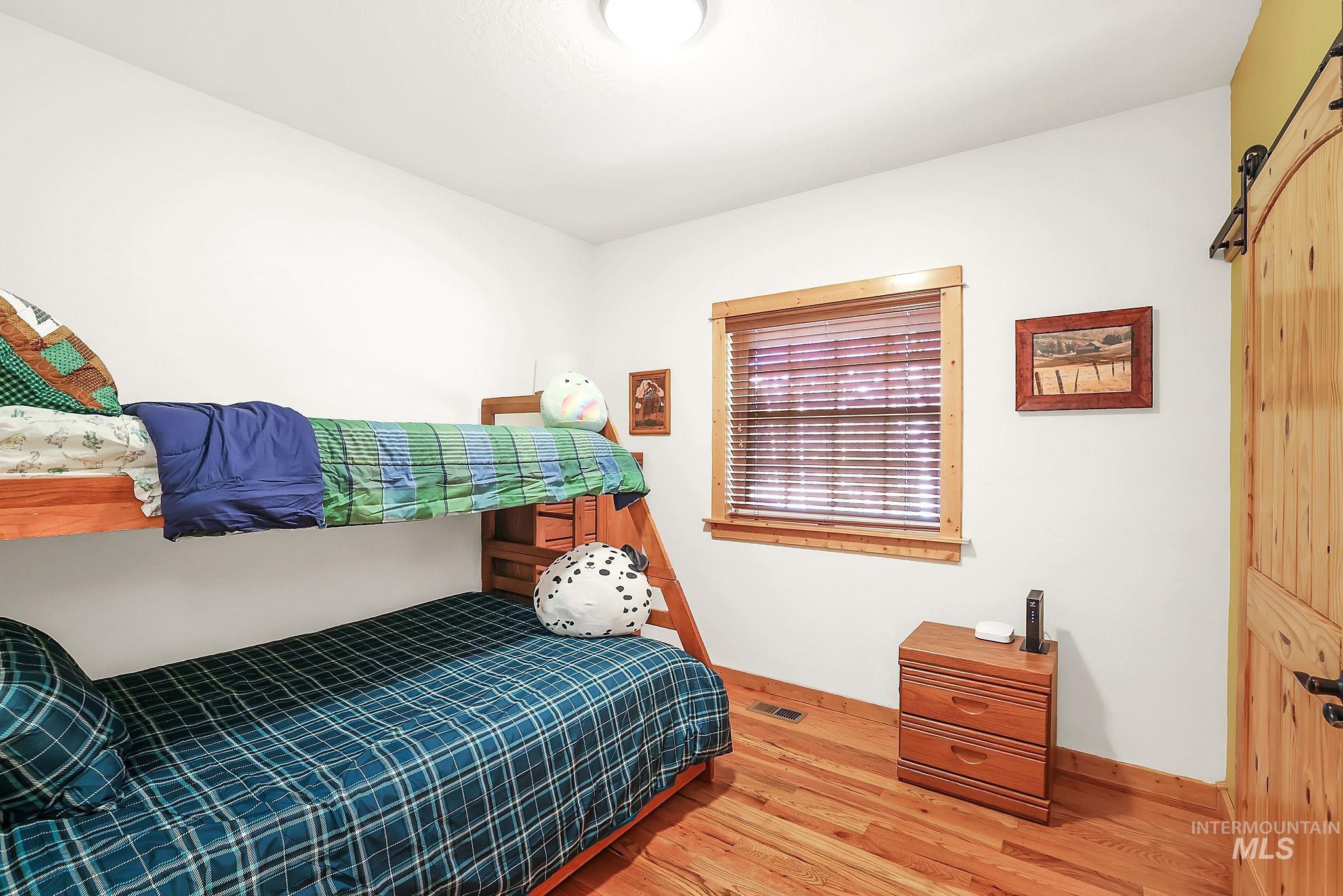 Bedroom with light wood-type flooring and a barn door