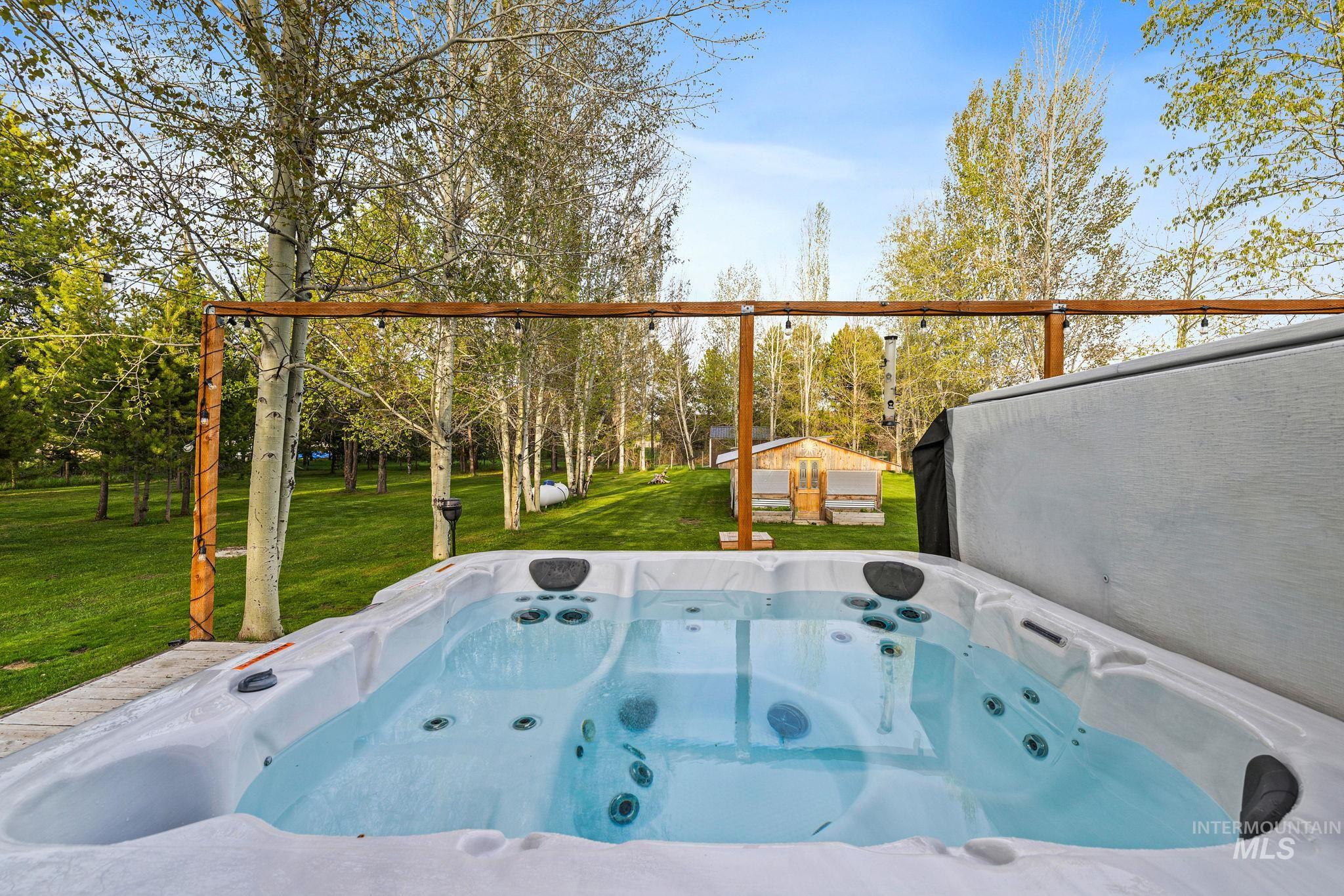 View of patio / terrace featuring a hot tub and an outdoor structure