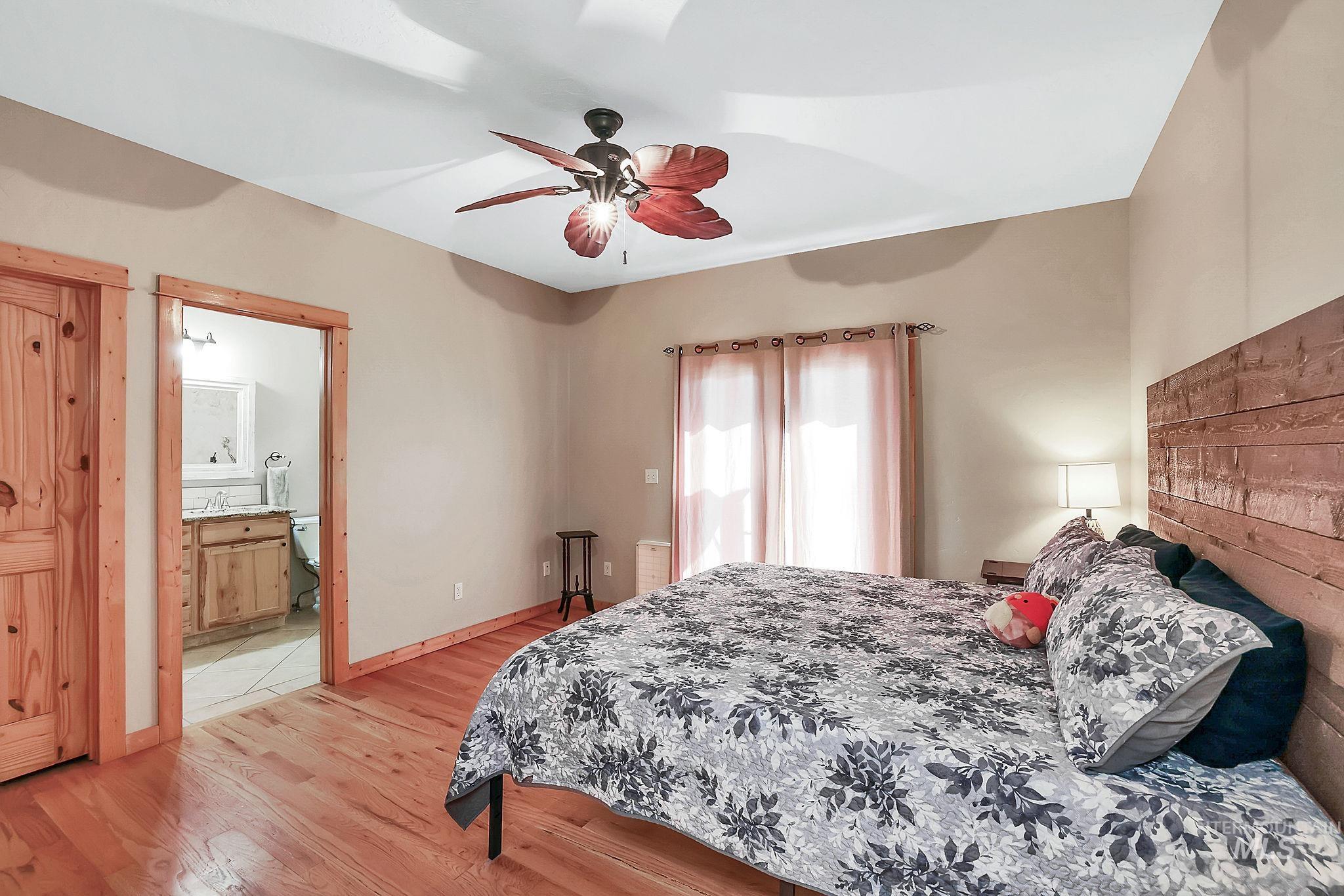 Bedroom featuring light wood-style floors, ceiling fan, and ensuite bathroom