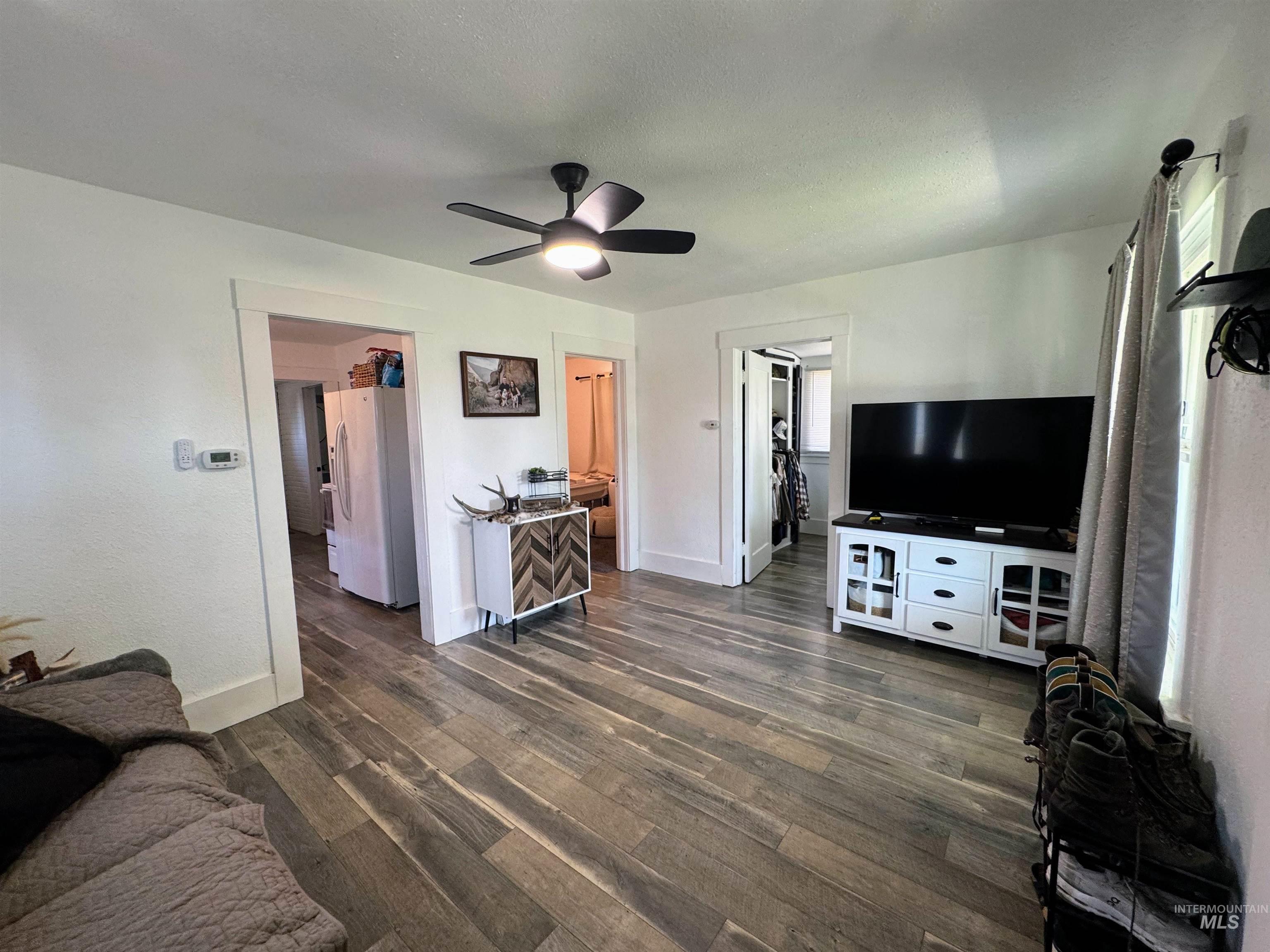 Living room with dark wood-style flooring, a ceiling fan, and a textured ceiling