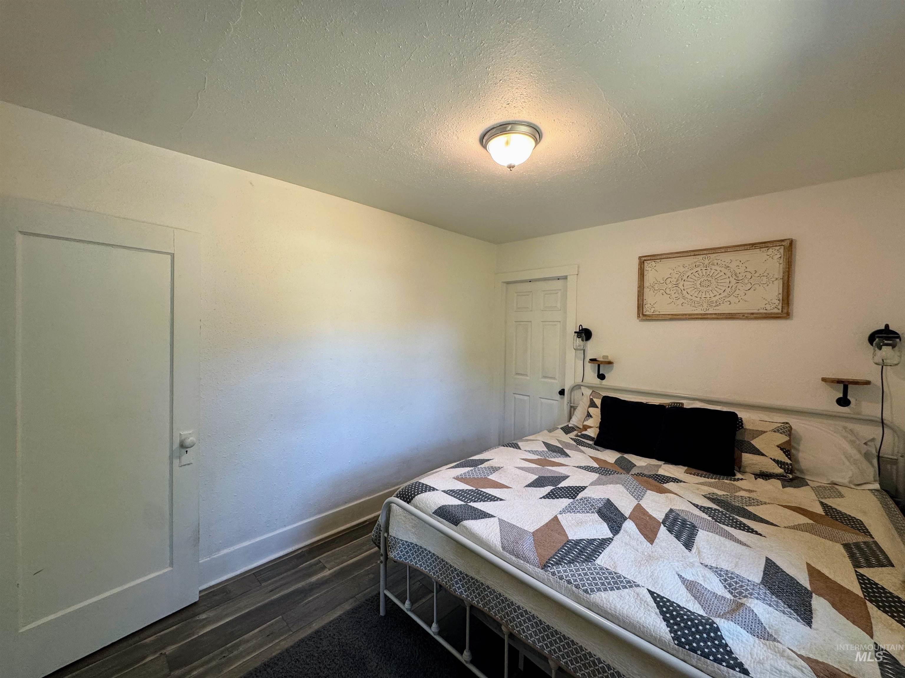 Bedroom with a textured ceiling and dark wood-type flooring