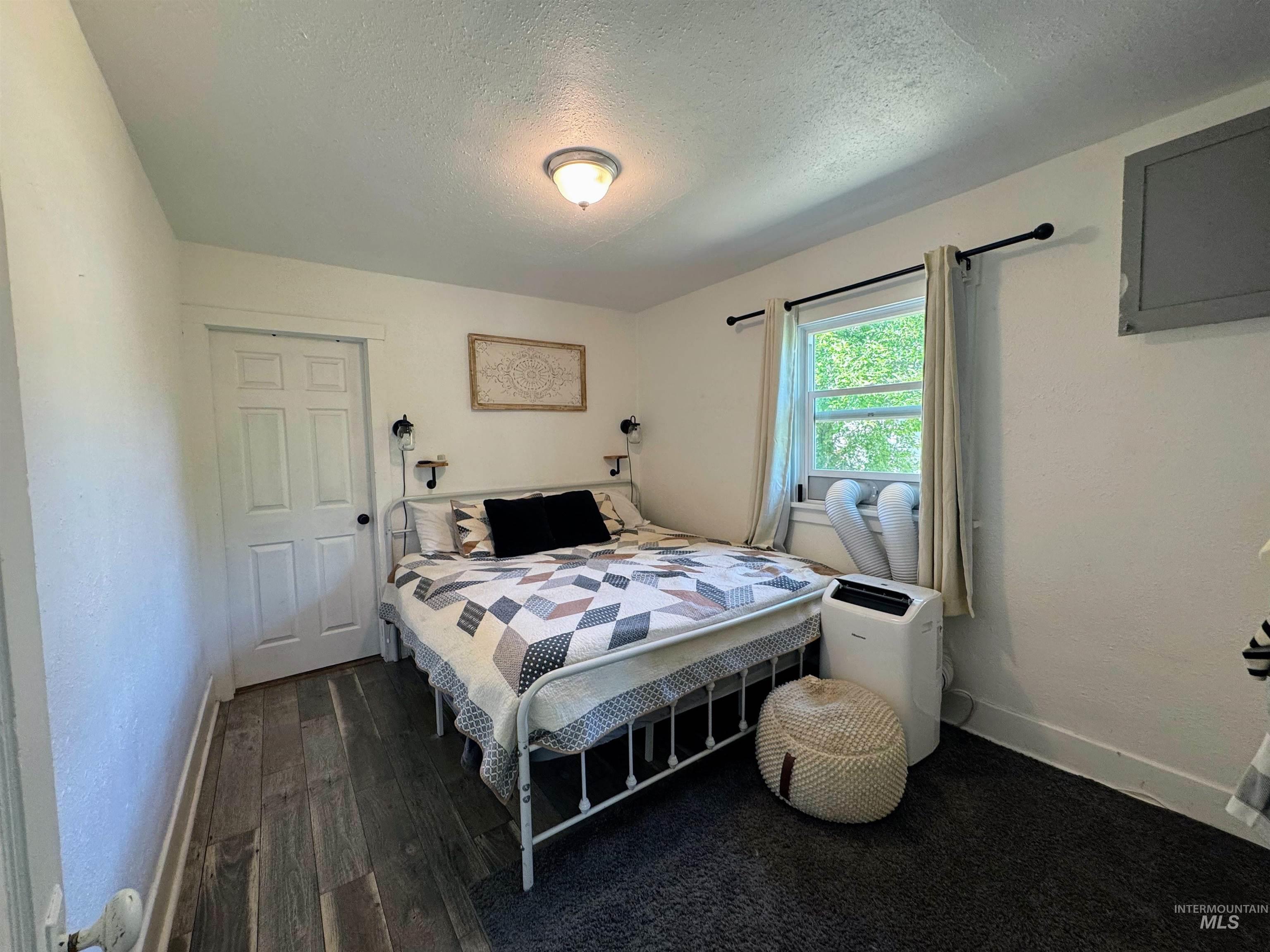 Bedroom featuring a textured ceiling and dark wood-type flooring
