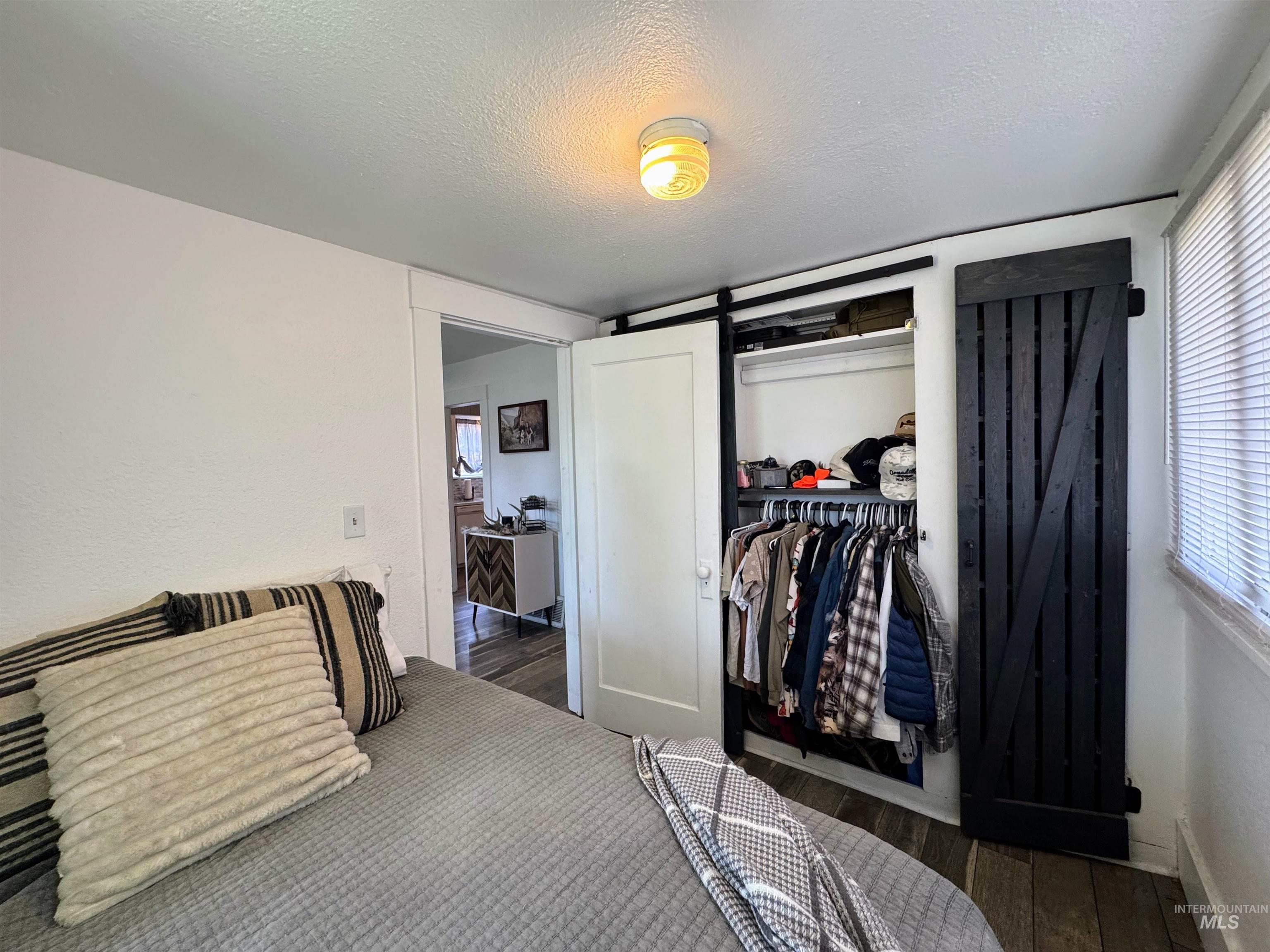 Bedroom with a textured ceiling, wood finished floors, and a closet