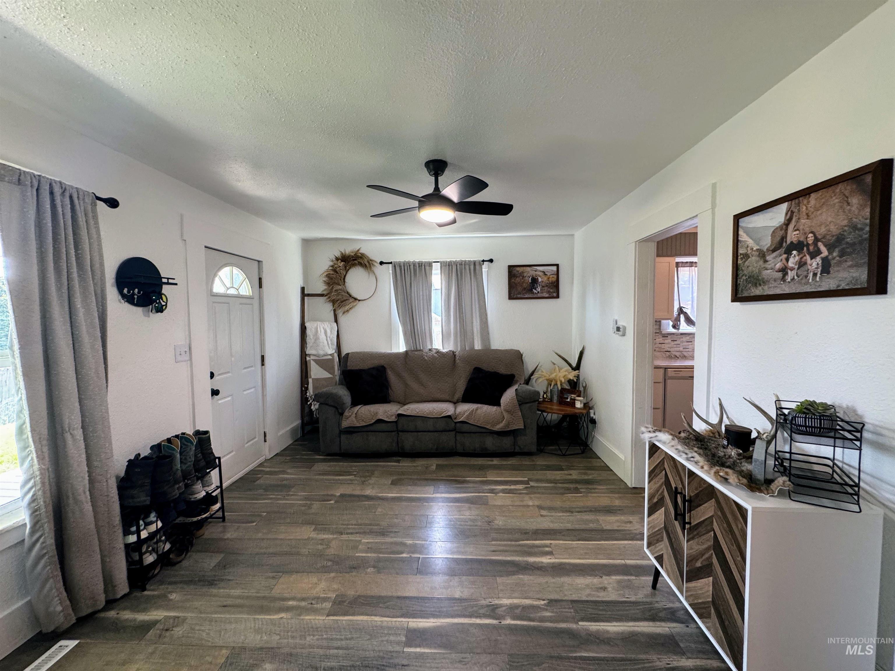 Living room featuring a textured ceiling, dark wood-style flooring, and ceiling fan