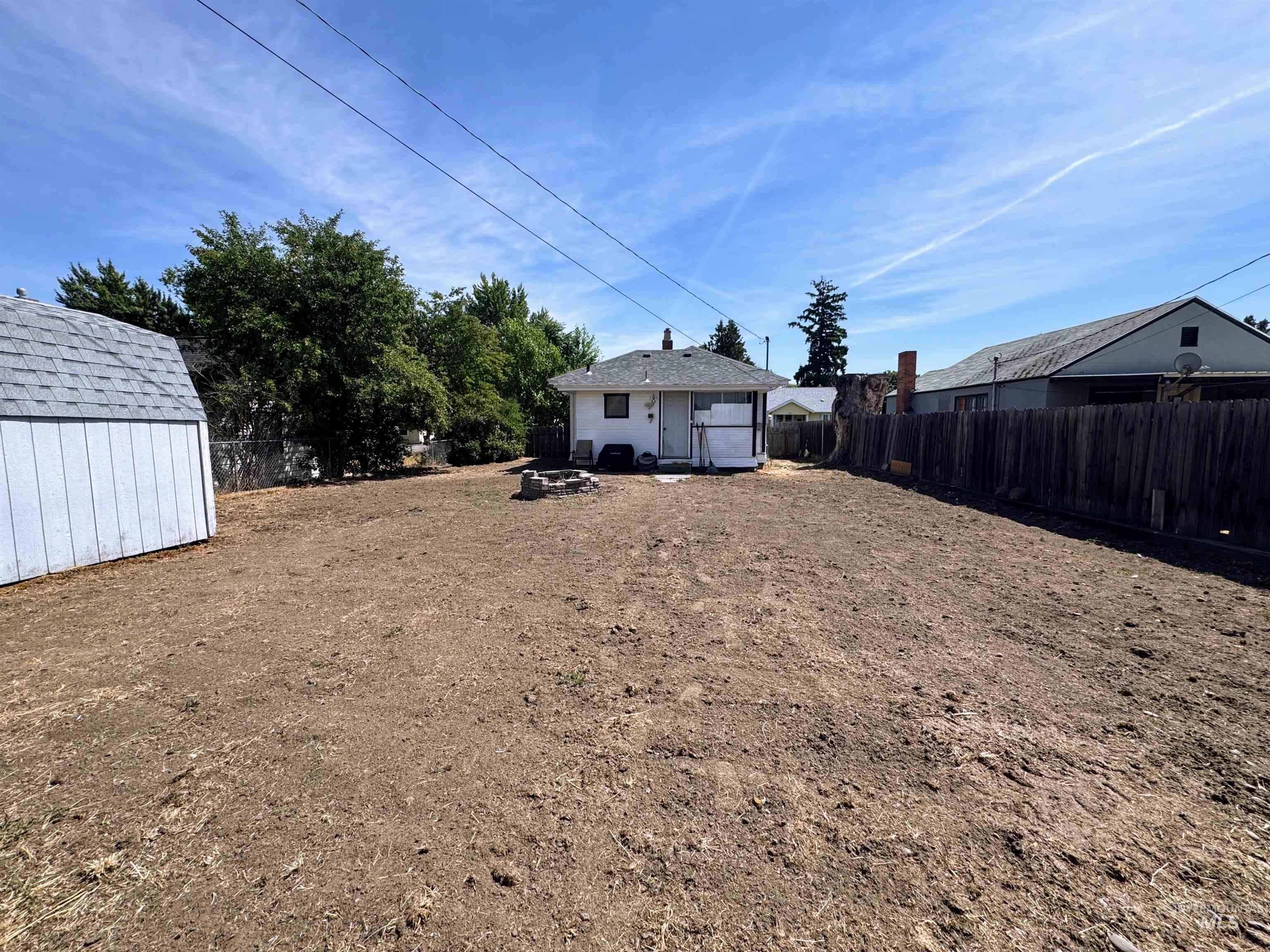 Fenced backyard with a storage unit and a fire pit