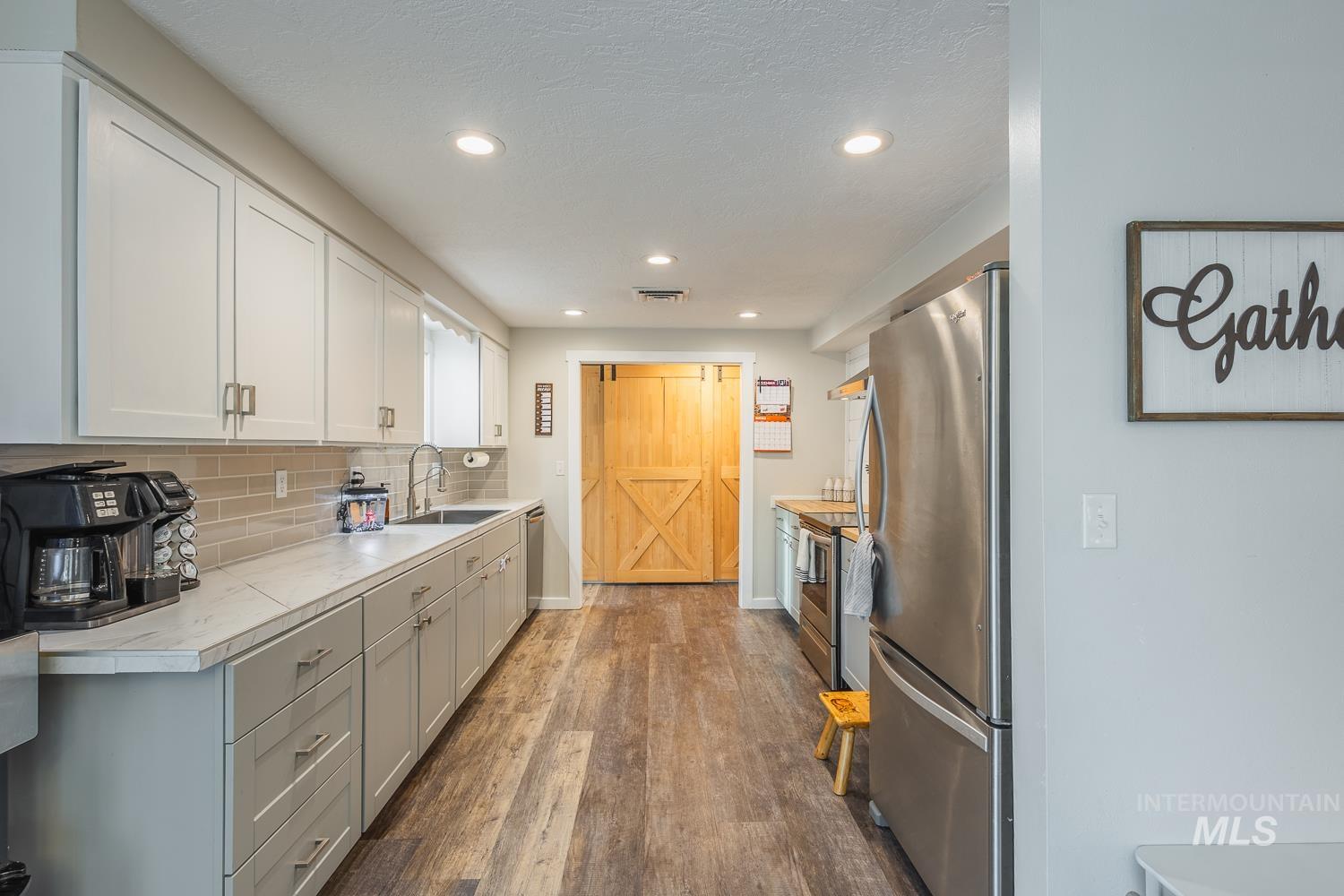 Kitchen with light countertops, appliances with stainless steel finishes, dark wood finished floors, decorative backsplash, and recessed lighting