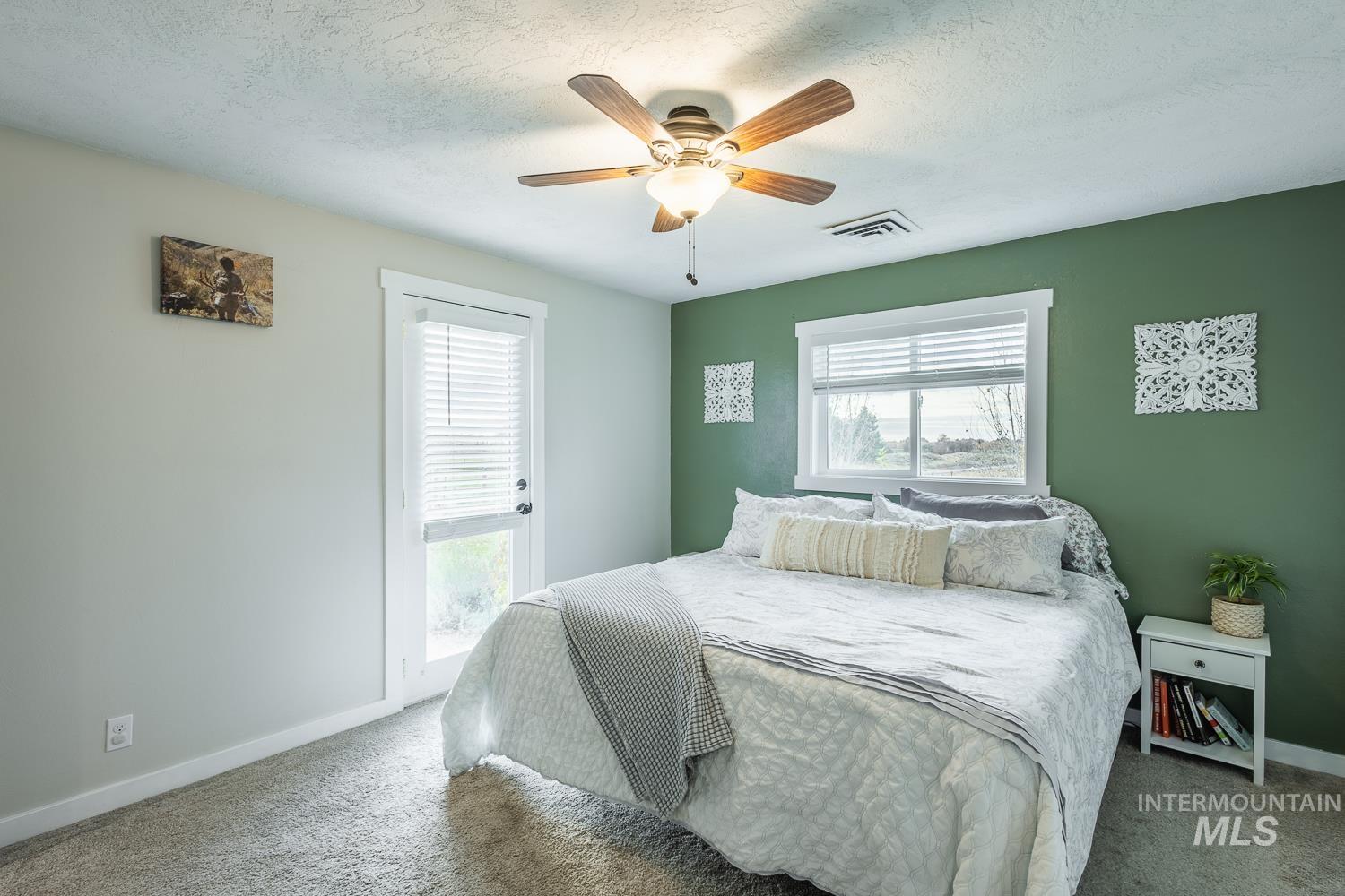 Carpeted bedroom with multiple windows, a ceiling fan, and a textured ceiling