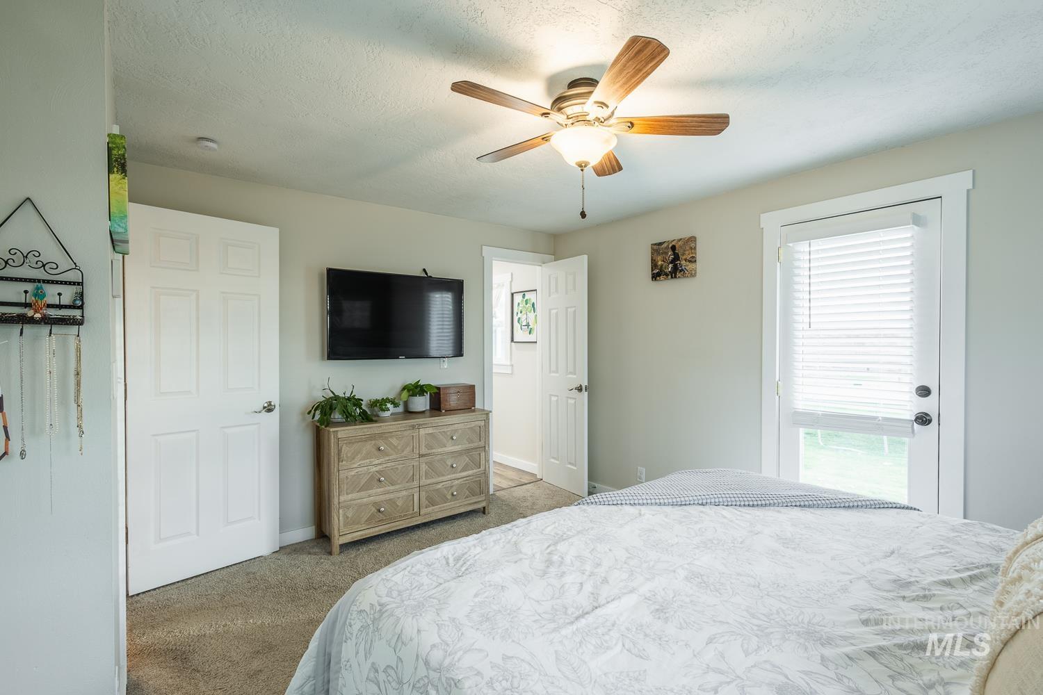 Bedroom featuring light colored carpet, a ceiling fan, and a textured ceiling