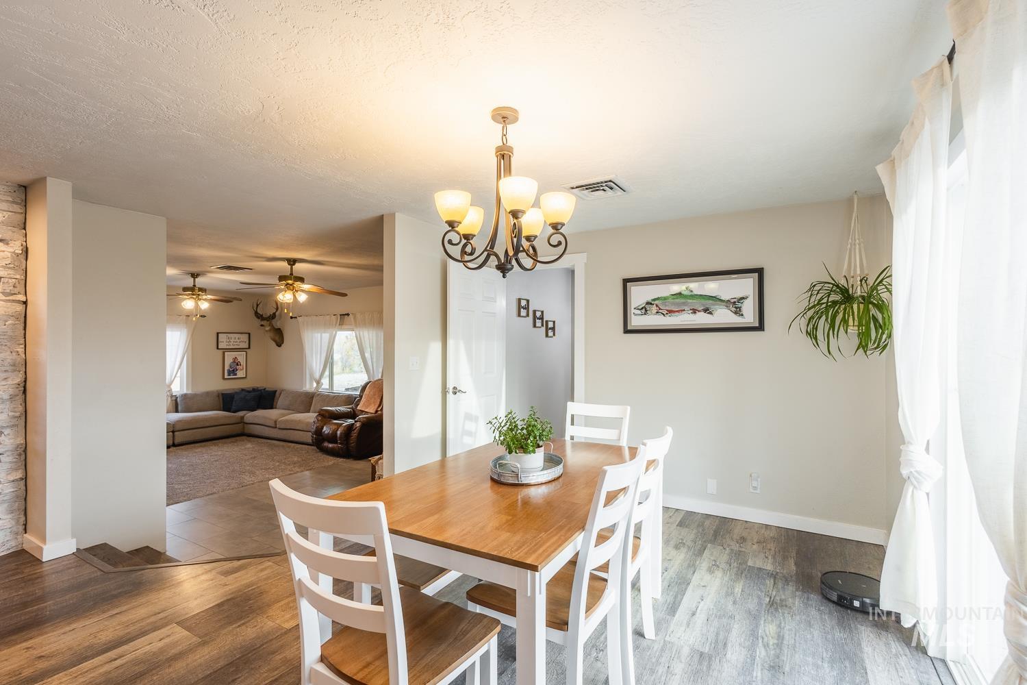 Dining area with wood finished floors, a chandelier, a textured ceiling, and ceiling fan