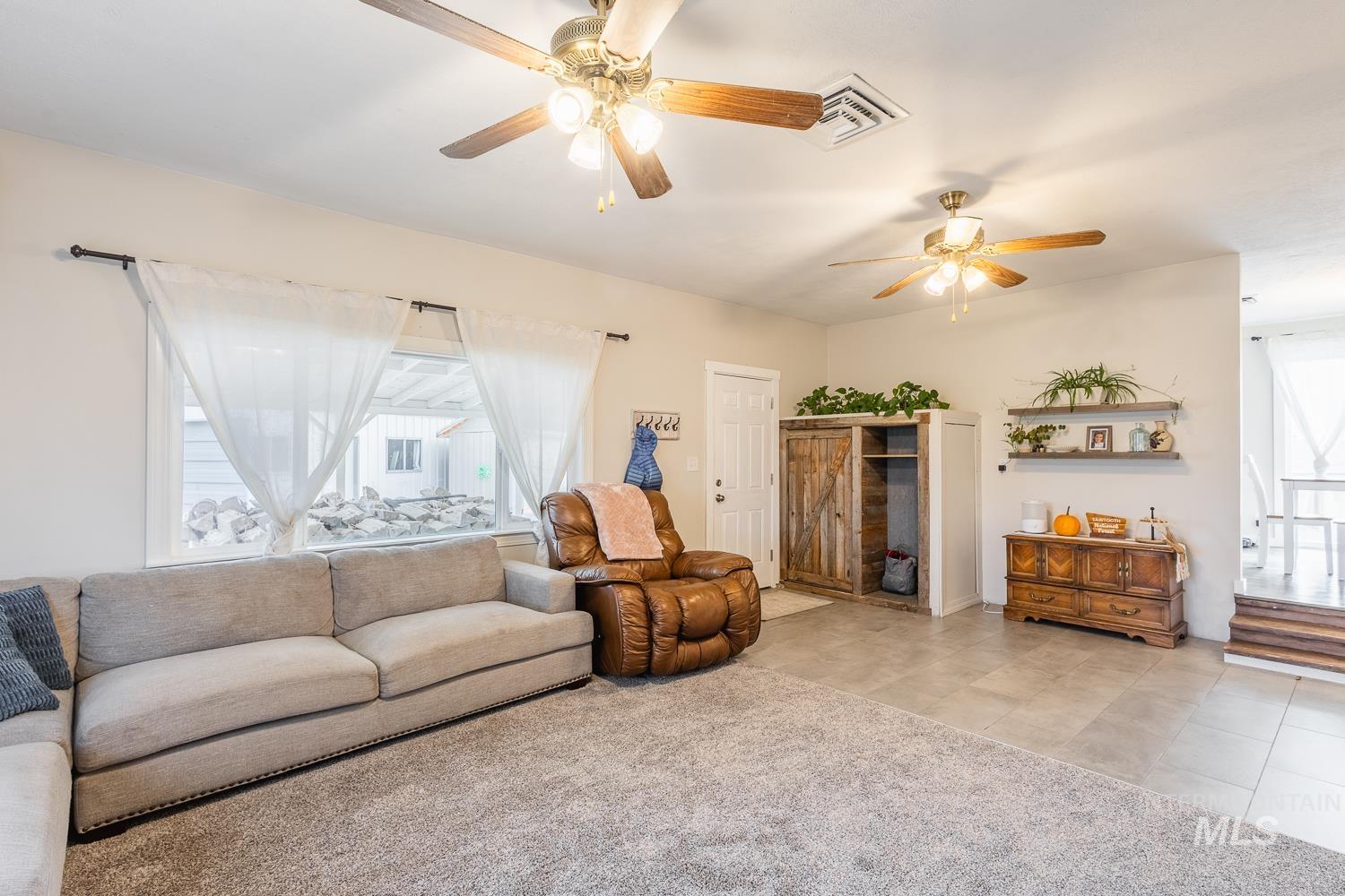 Carpeted living area with a ceiling fan and tile patterned floors