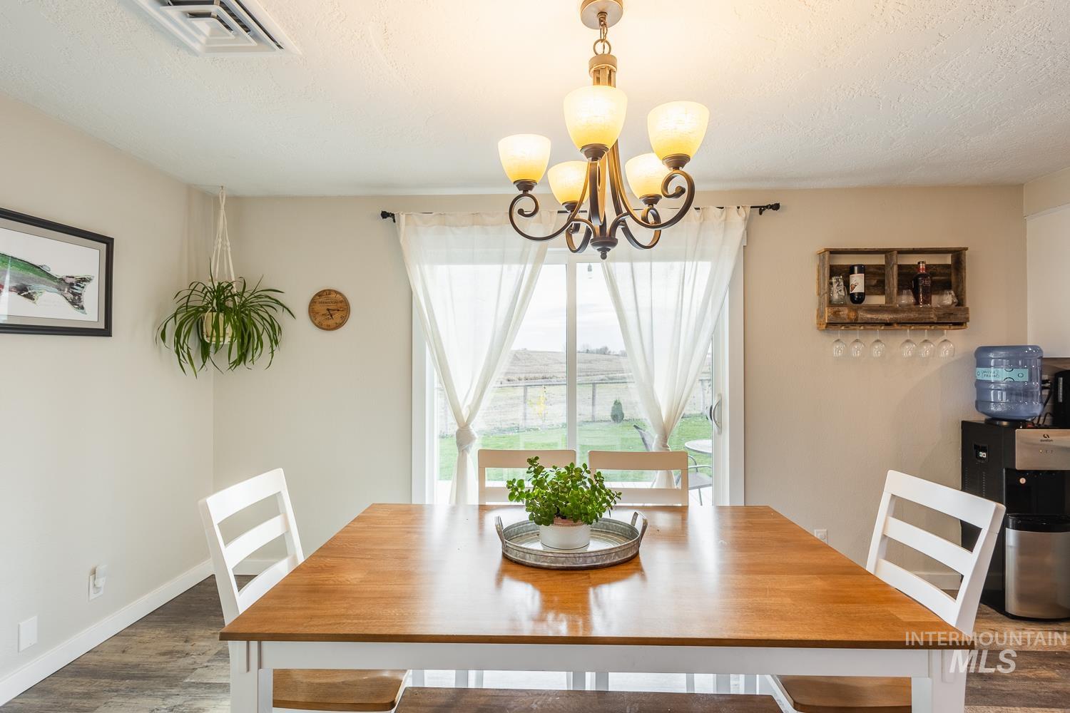 Dining space with a chandelier, wood finished floors, and a textured ceiling