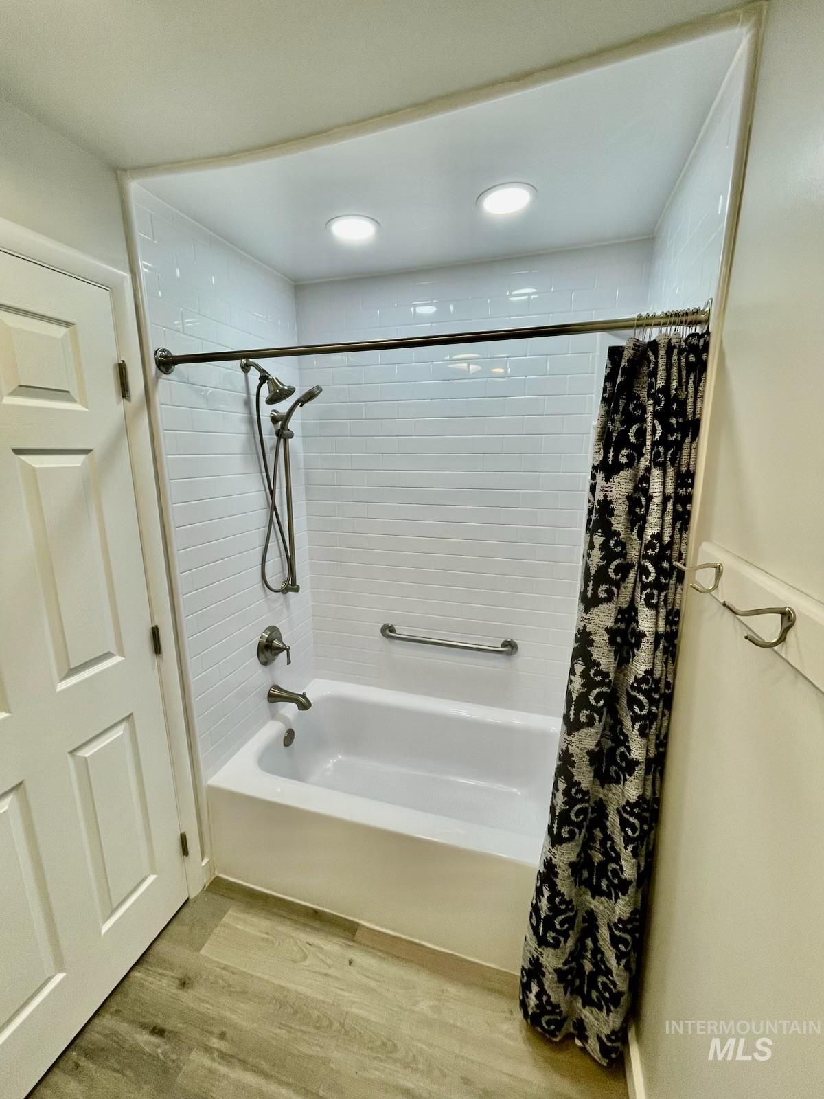 Bathroom featuring light wood finished floors, shower / tub combo with curtain, and recessed lighting