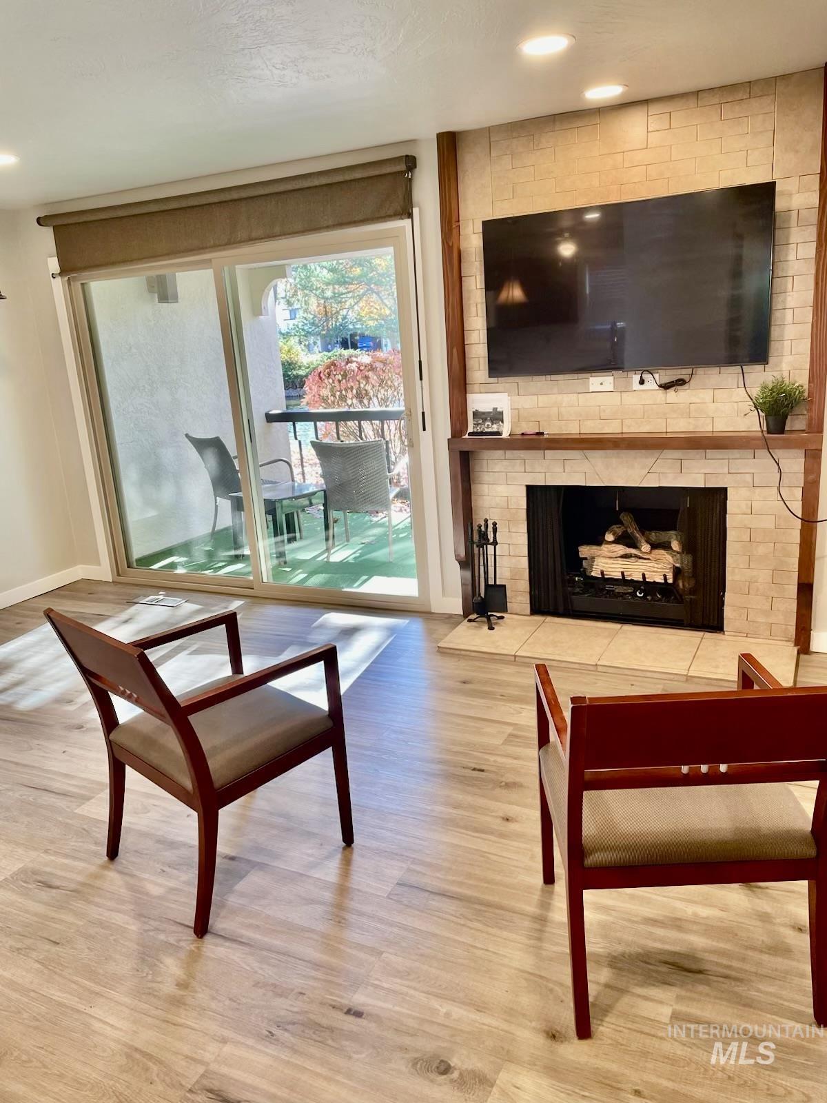 Living room with light wood-type flooring, a brick fireplace, and recessed lighting
