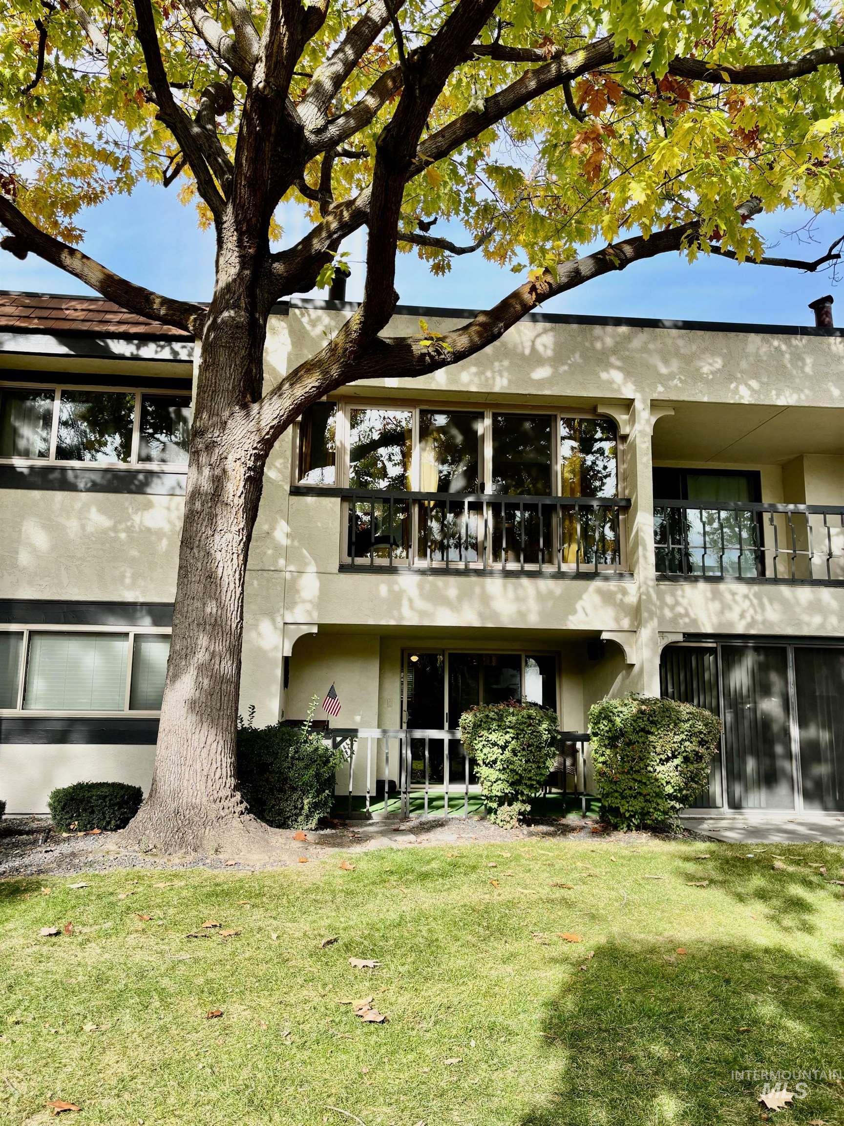 Back of house with stucco siding, a balcony, a yard, and a patio area