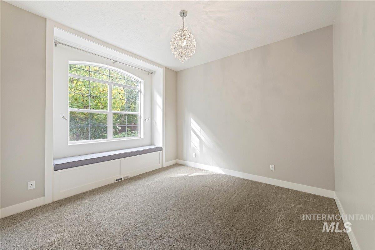 Unfurnished room with carpet and a chandelier