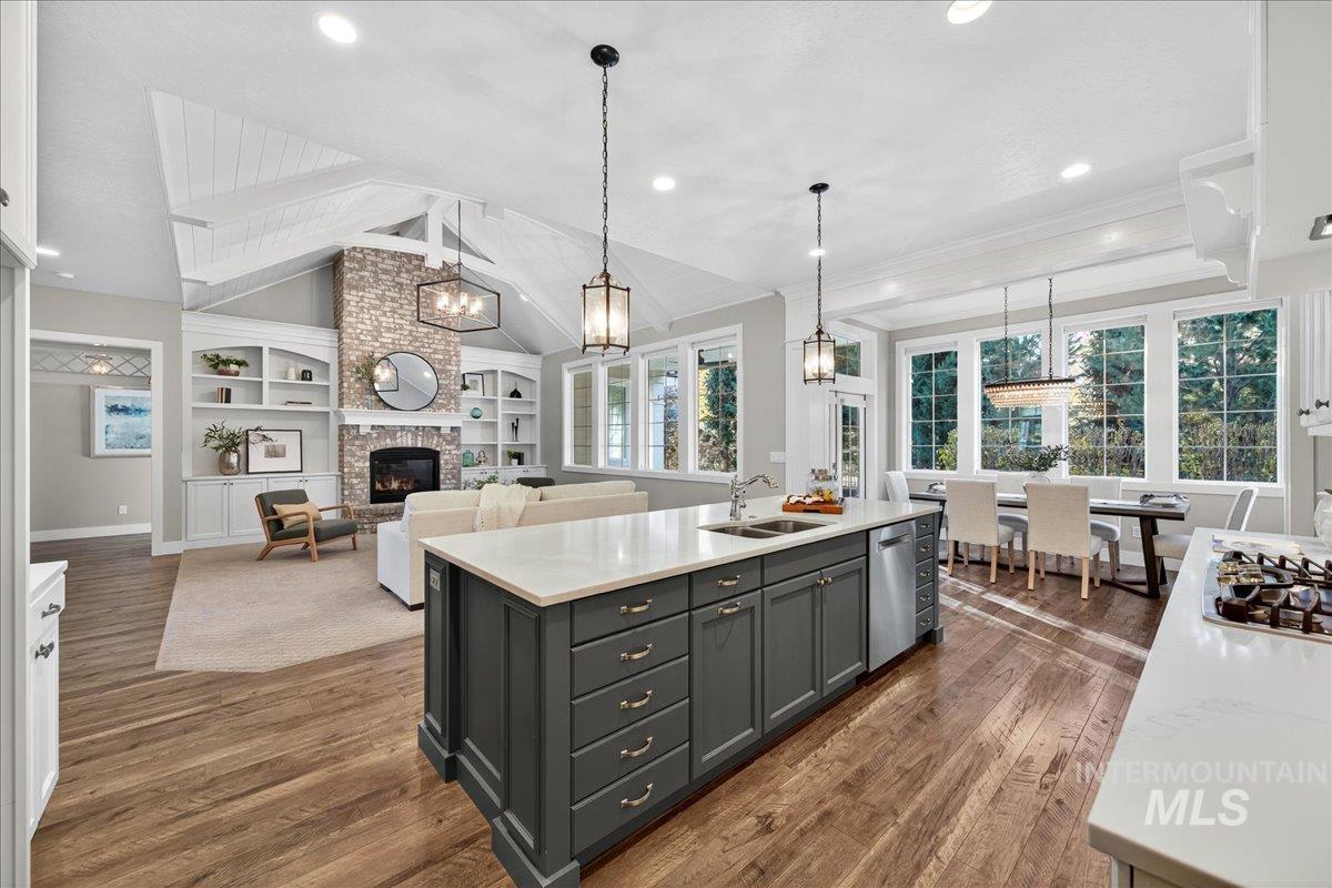 Kitchen with a brick fireplace, decorative light fixtures, light stone counters, built in shelves, and dark wood finished floors