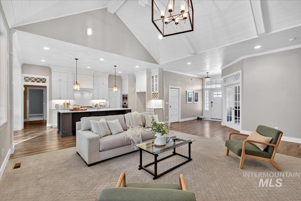 Living area featuring beam ceiling, wood finished floors, a chandelier, high vaulted ceiling, and recessed lighting