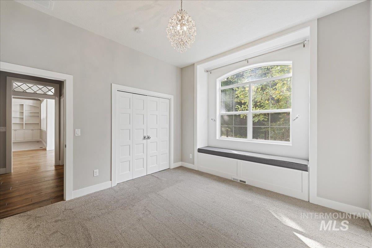 Unfurnished bedroom with carpet, a chandelier, and a closet